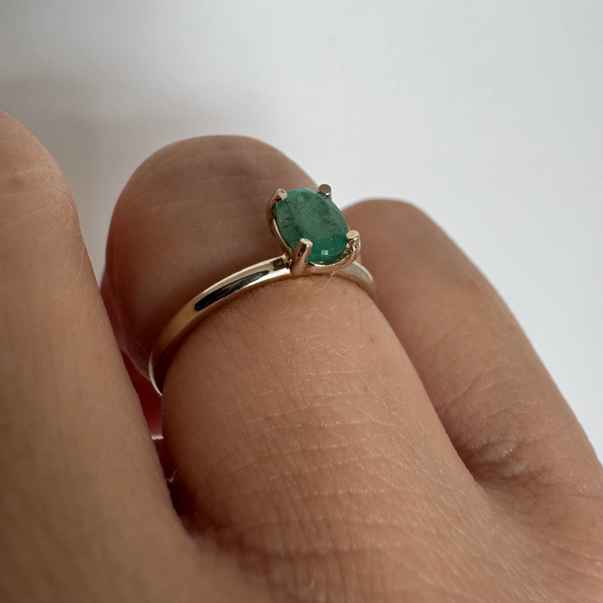 14K gold ring set with an oval-cut Emerald