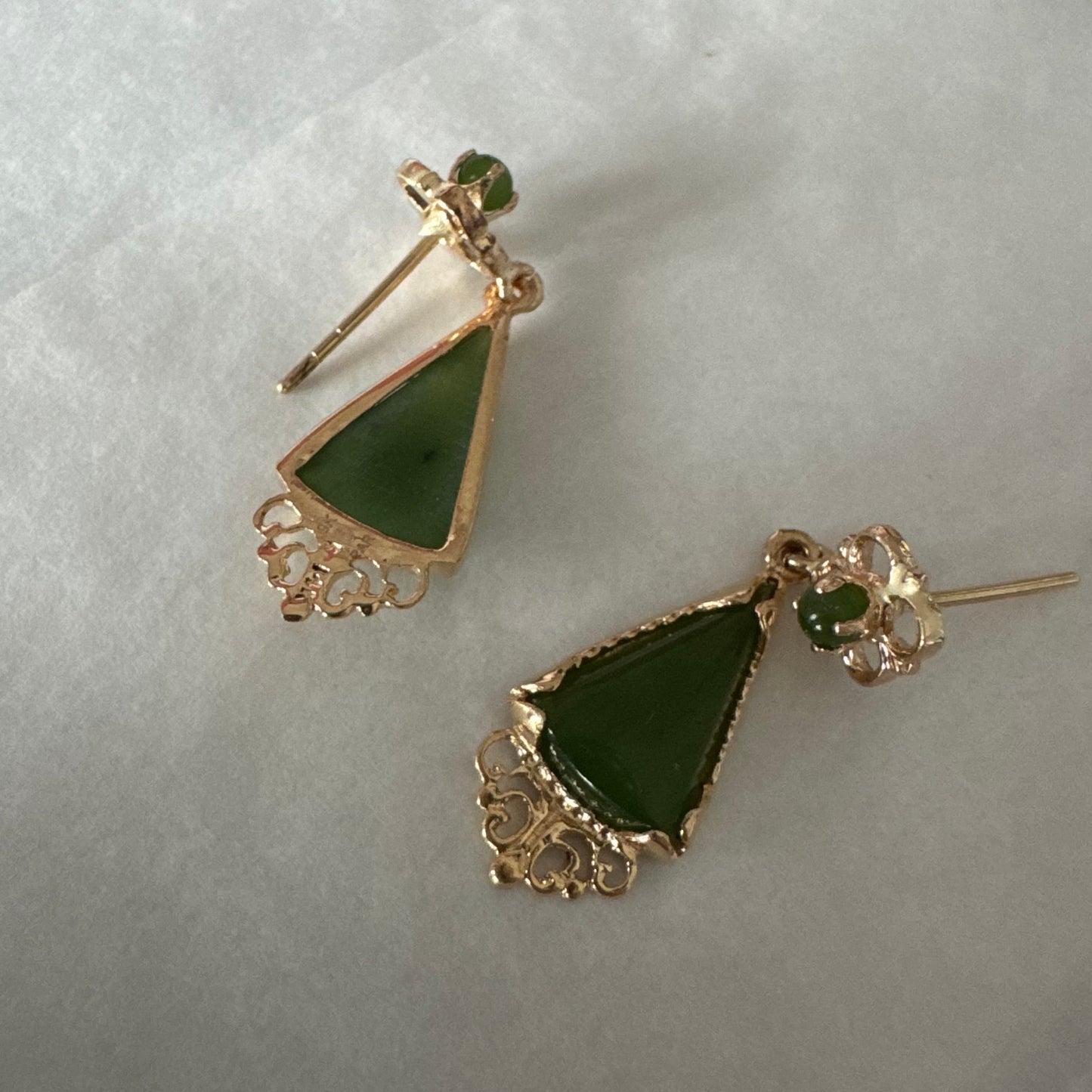 עגילי זהב צהוב 14 קראט משובצים אבני ג׳ייד ירוקות בגוון עמוק בחיתוך משולש.