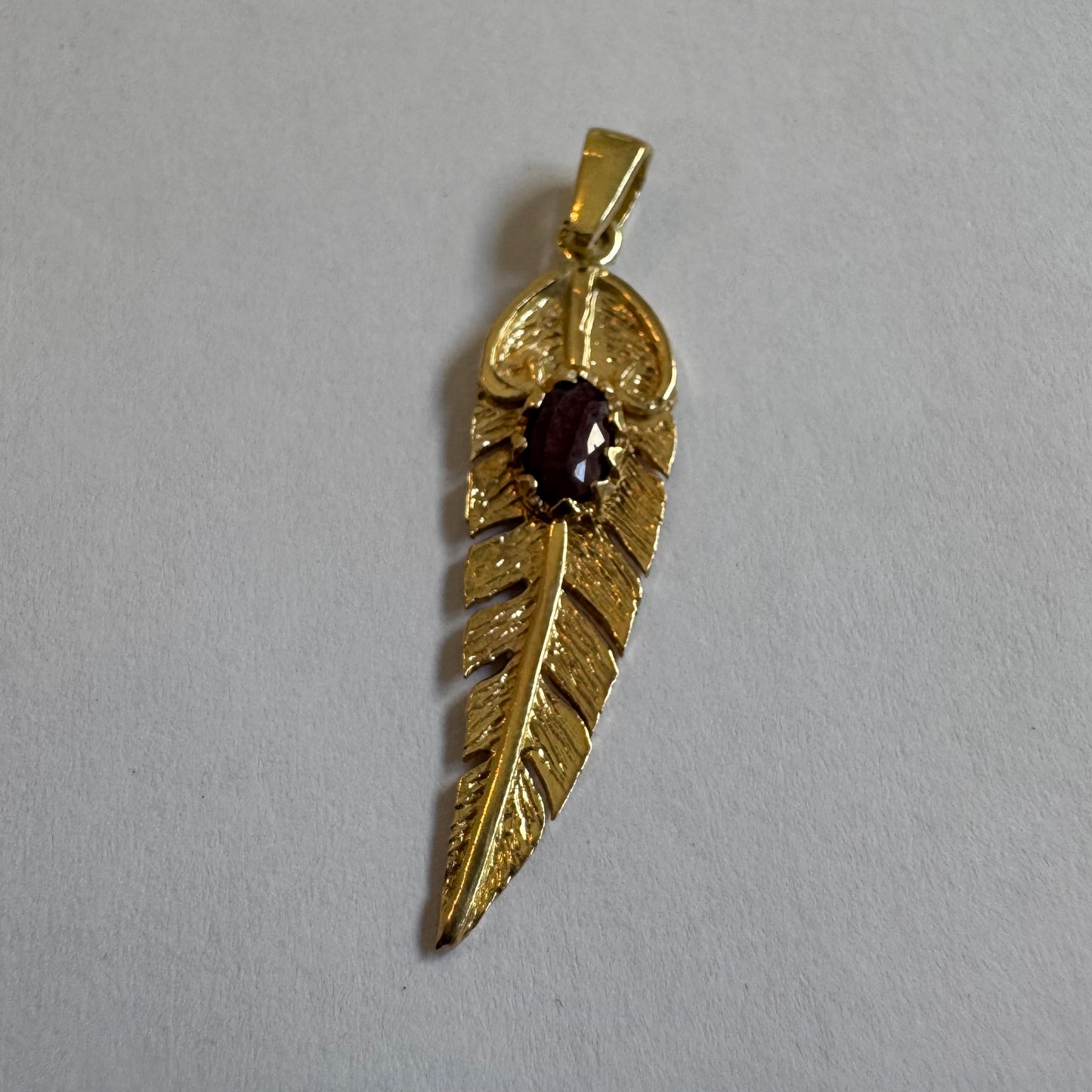 14K gold feather pendant set with a unique Ruby at its center.