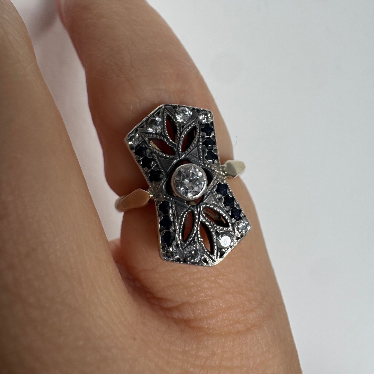 14K gold Art Deco ring set with a central Diamond, framed by deep blue Sapphires and accent Diamonds.