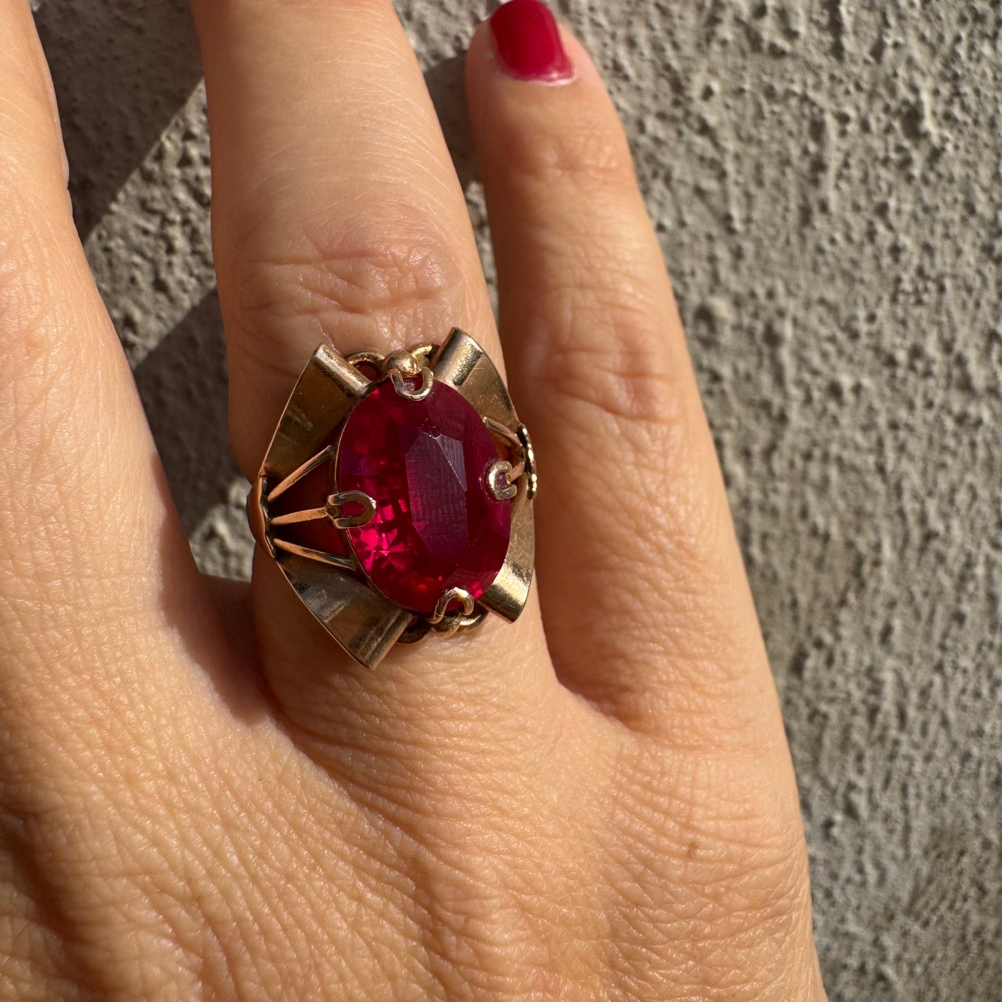 טבעת זהב 14 קראט משובצת אבן אובלית גדולה בצבע אדום חי במסגרת גאומטרית מיוחדת.