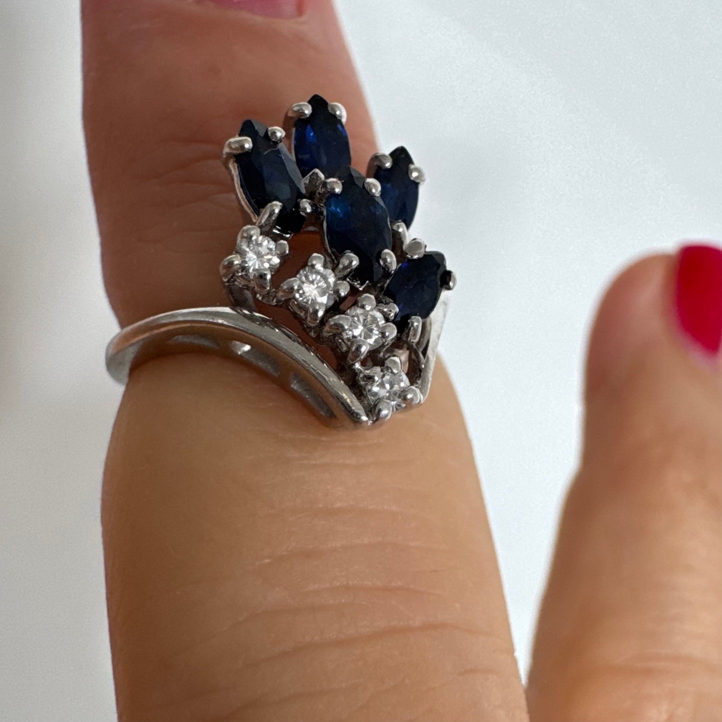 טבעת זהב לבן 14 קראט משובצת אבני ספיר כחולות בחיתוך מרקיזה ויהלומים, היוצרים מראה אלגנטי ודינמי.