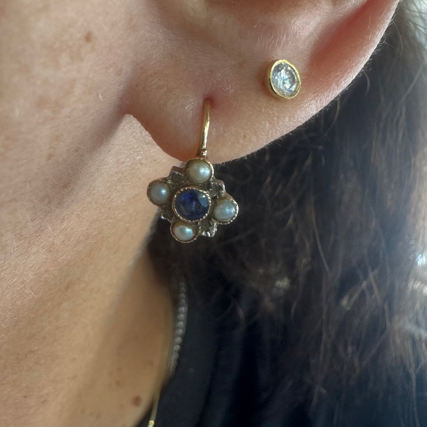 14K gold earrings featuring a round deep blue Sapphire in the center, surrounded by Pearls arranged in a floral design.