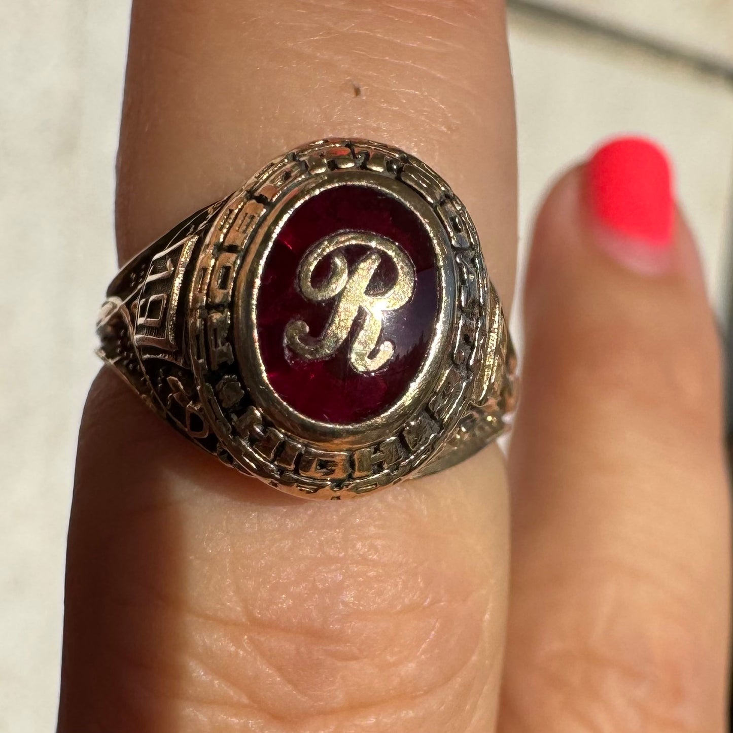10K gold class ring featuring a rich red center stone engraved with the letter “R”.