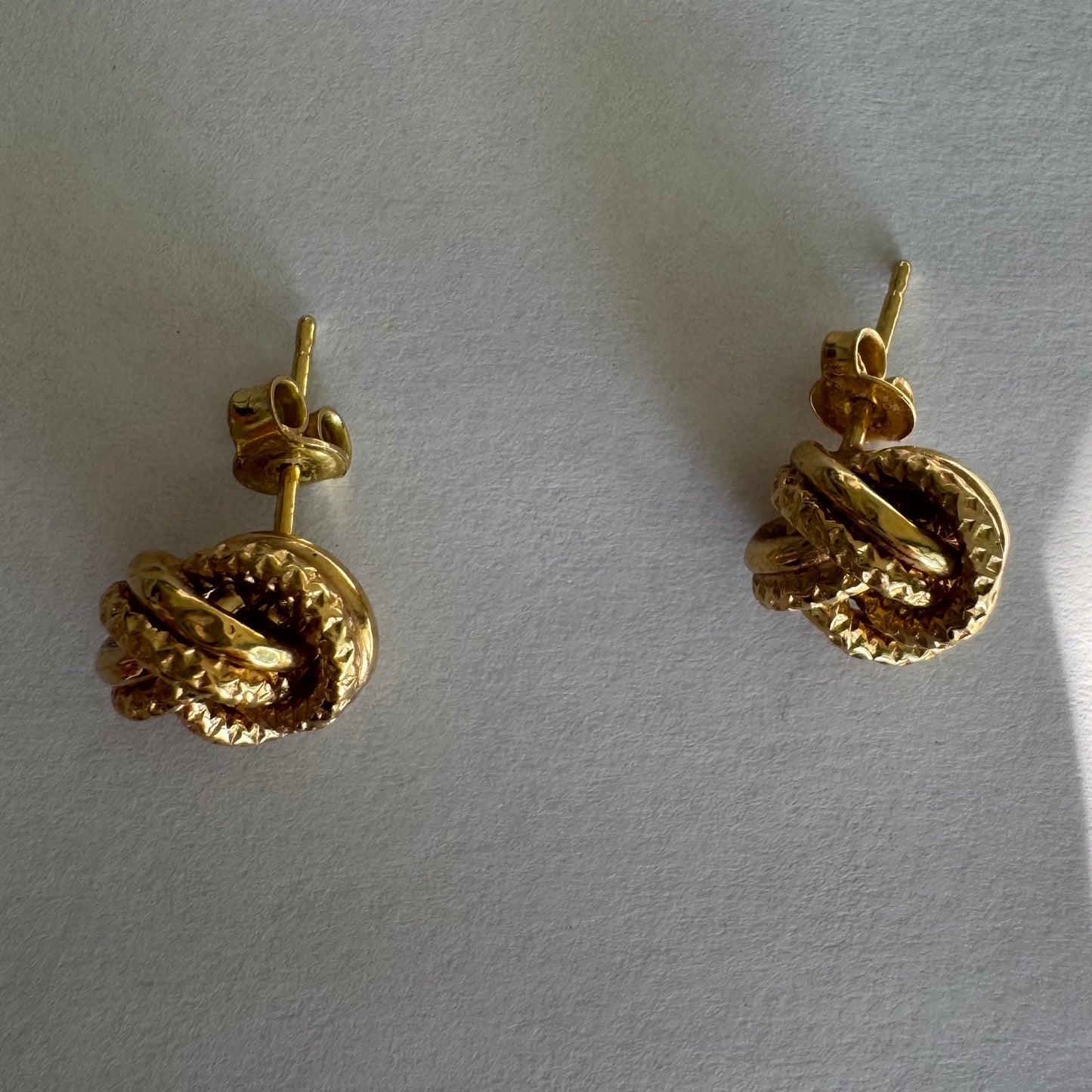 עגילי זהב צהוב 18 קראט בעיצוב קשר פיסולי, עם טקסטורה עשירה המדגישה את עומק וצורת הזהב.