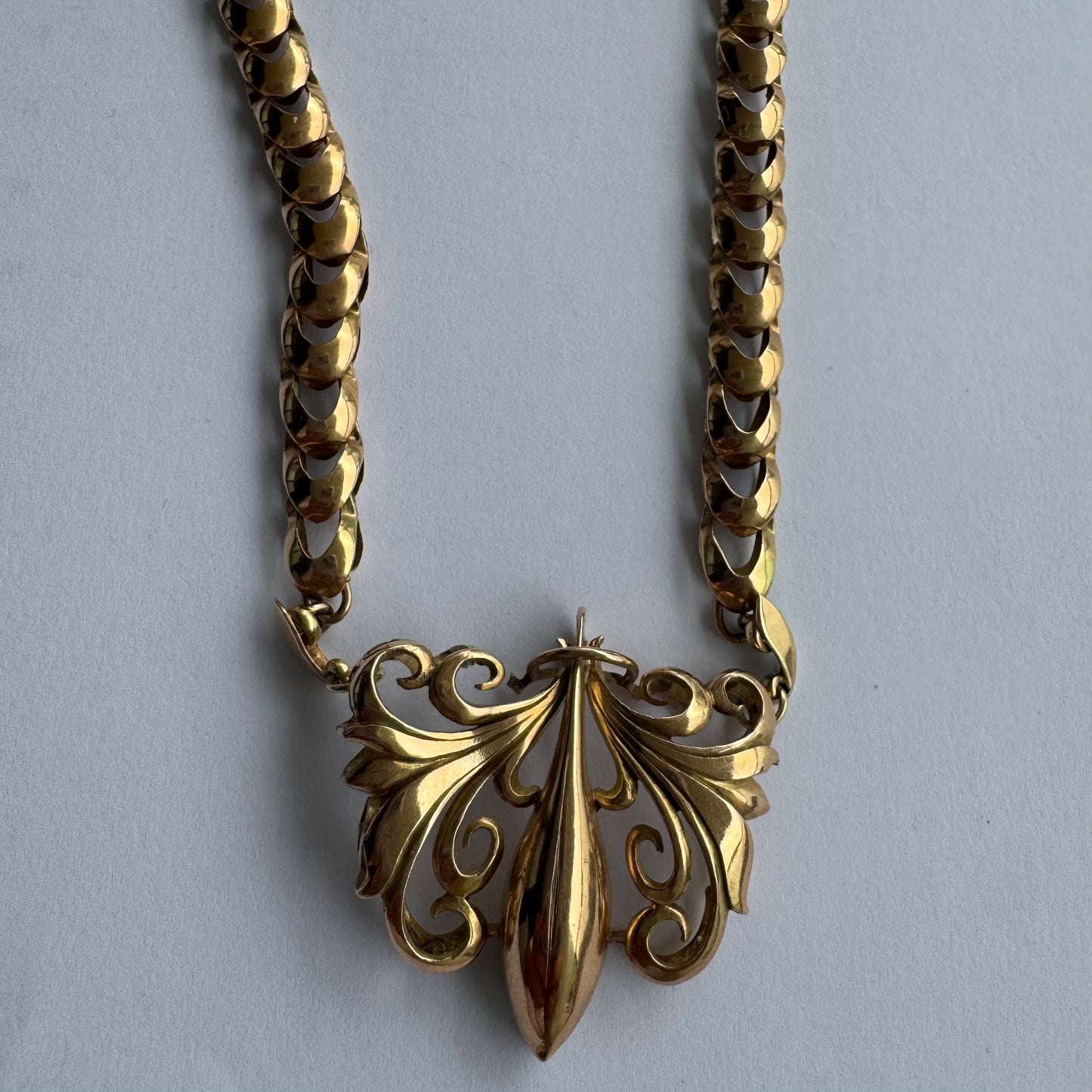 שרשרת זהב 14 קראט בעלת עיטור פלר דה ליס (Fleur-de-lis) אמנותי, המעוצב בקווים מעוגלים של עלי שושן בסגנון אר נובו.