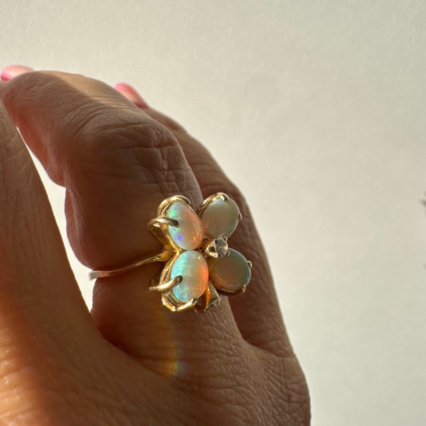 טבעת זהב 14 קראט בעיצוב פרח, משובצת ארבע אבני אופל בחיתוך טיפה ובמרכז יהלום טבעי.