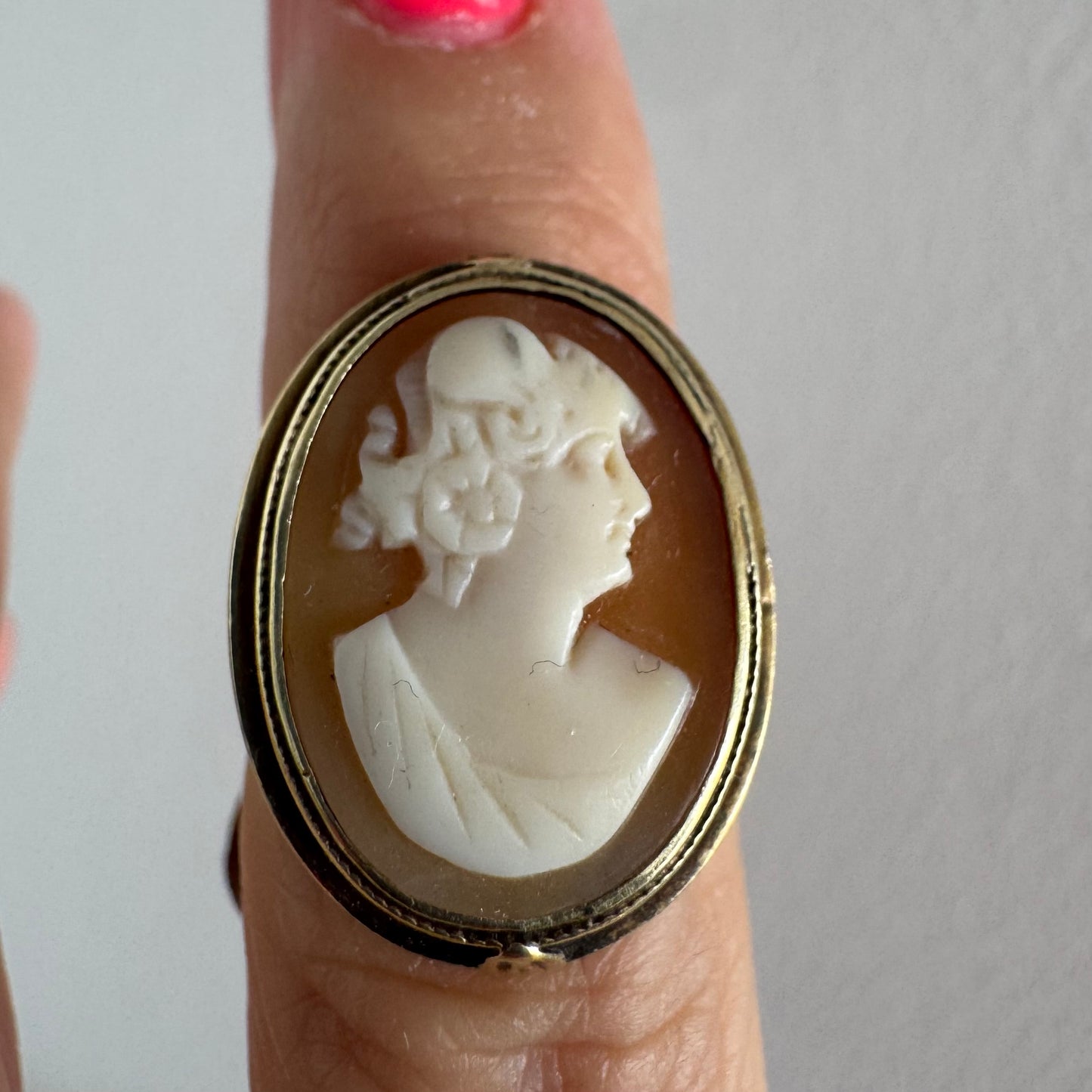 14K gold cameo ring featuring a finely carved portrait of a woman in profile, set in an oval bezel with intricate gold detailing