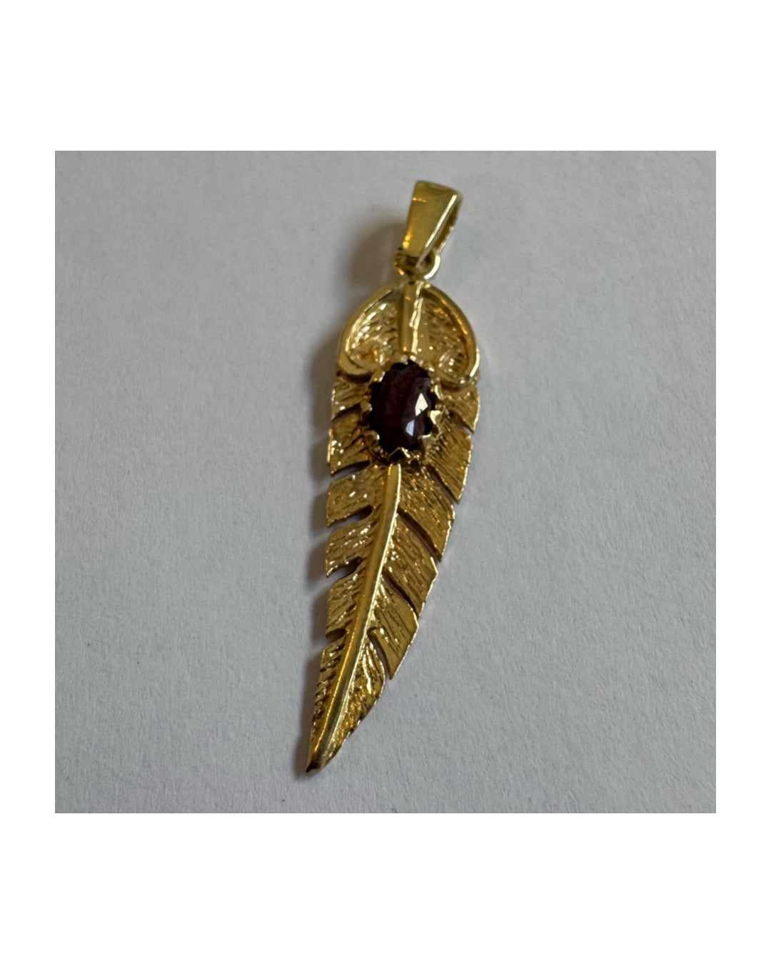 14K gold feather pendant set with a unique Ruby at its center.