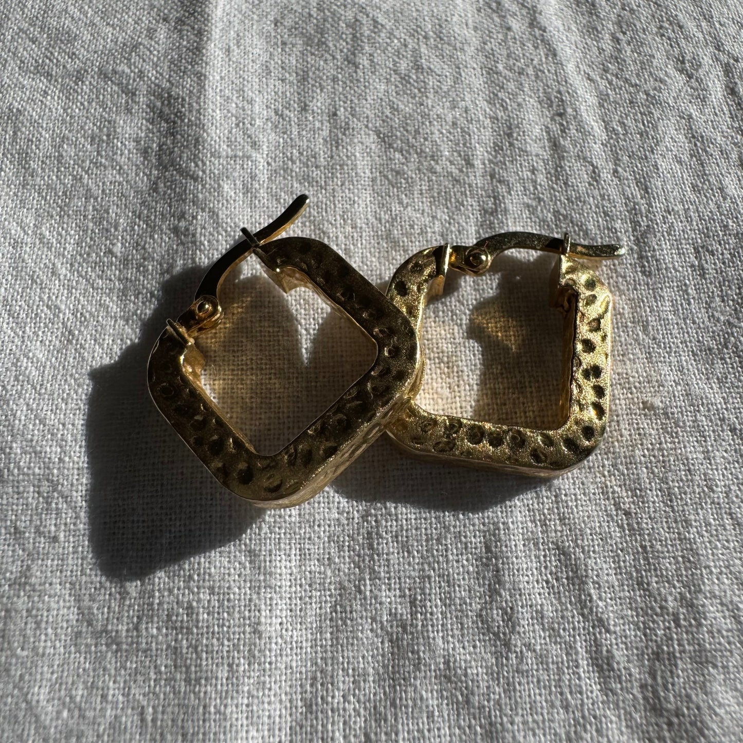 14K gold square hoop earrings with a textured, hammered finish.