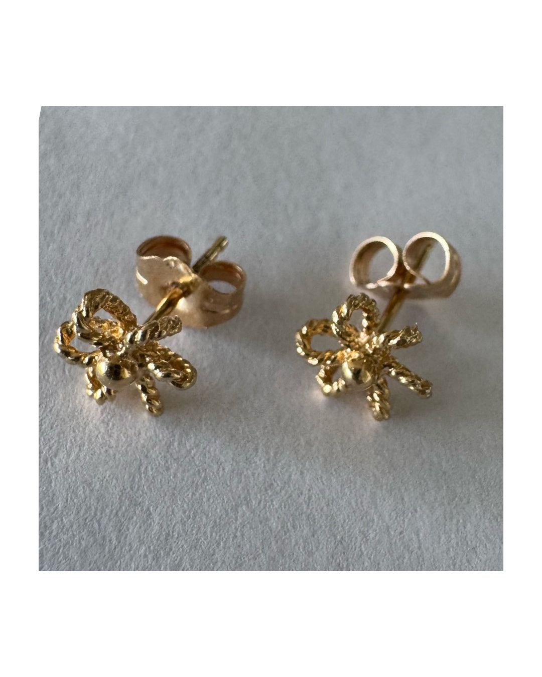 14K gold stud earrings designed as miniature flowers with fine textured details.