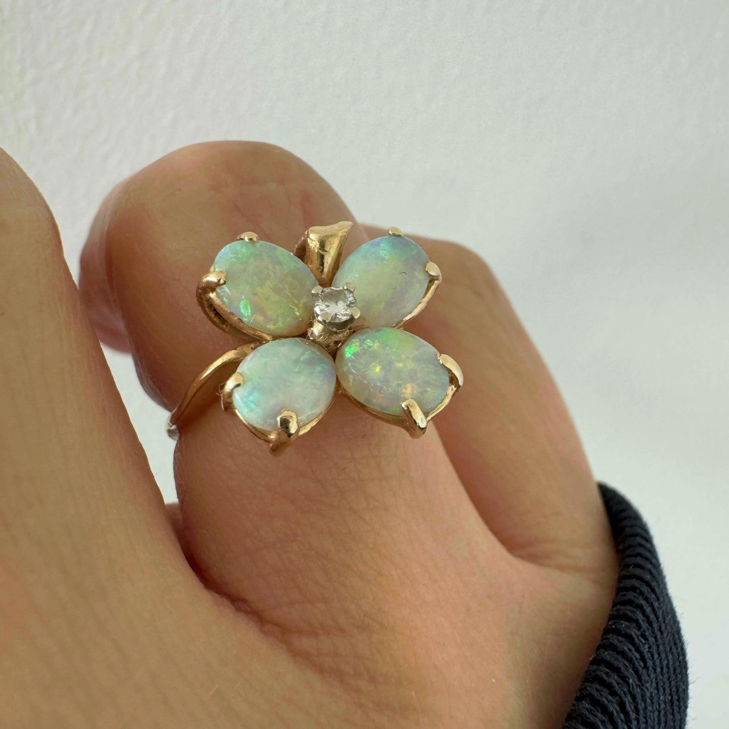 טבעת זהב 14 קראט בעיצוב פרח, משובצת ארבע אבני אופל בחיתוך טיפה ובמרכז יהלום טבעי.