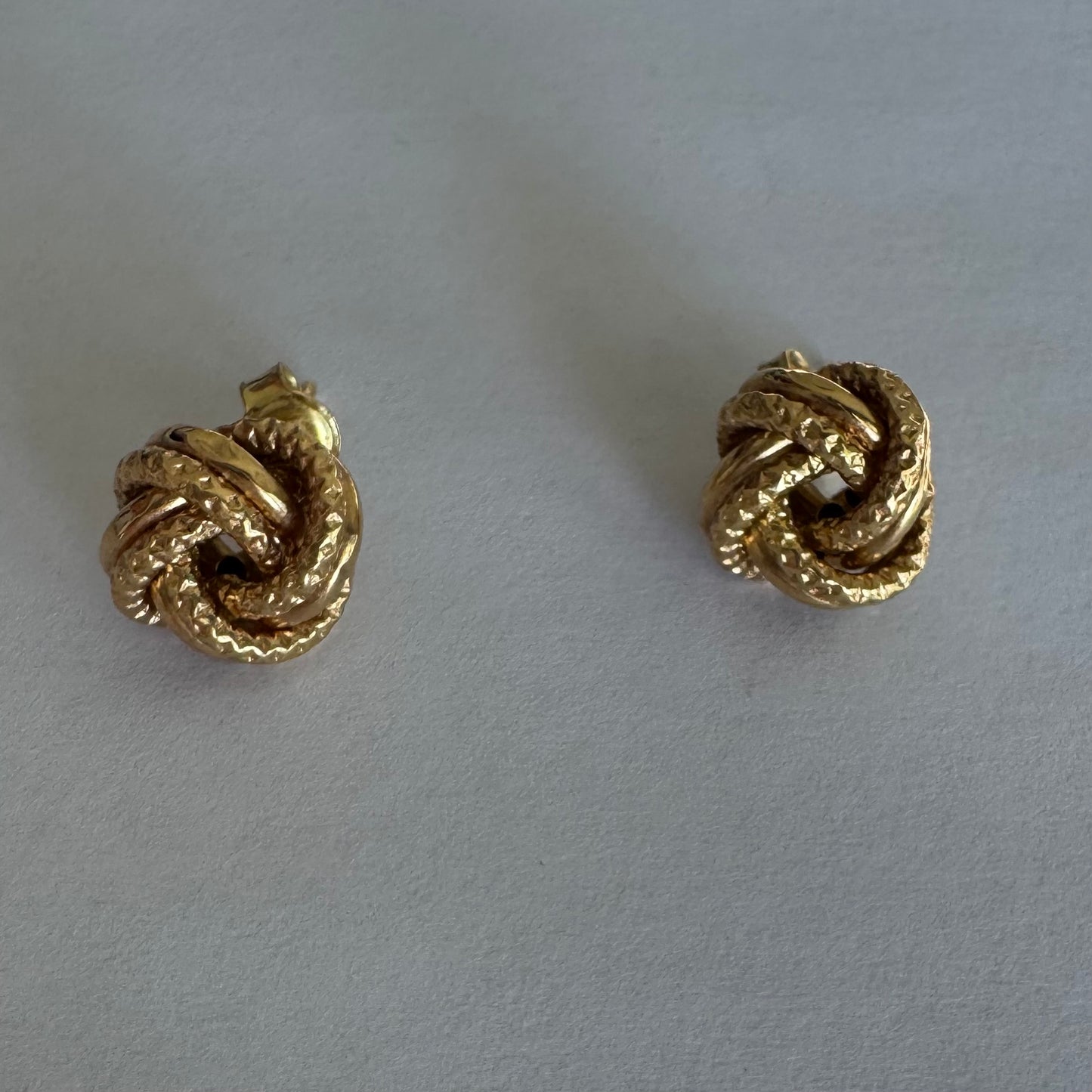 עגילי זהב צהוב 18 קראט בעיצוב קשר פיסולי, עם טקסטורה עשירה המדגישה את עומק וצורת הזהב.