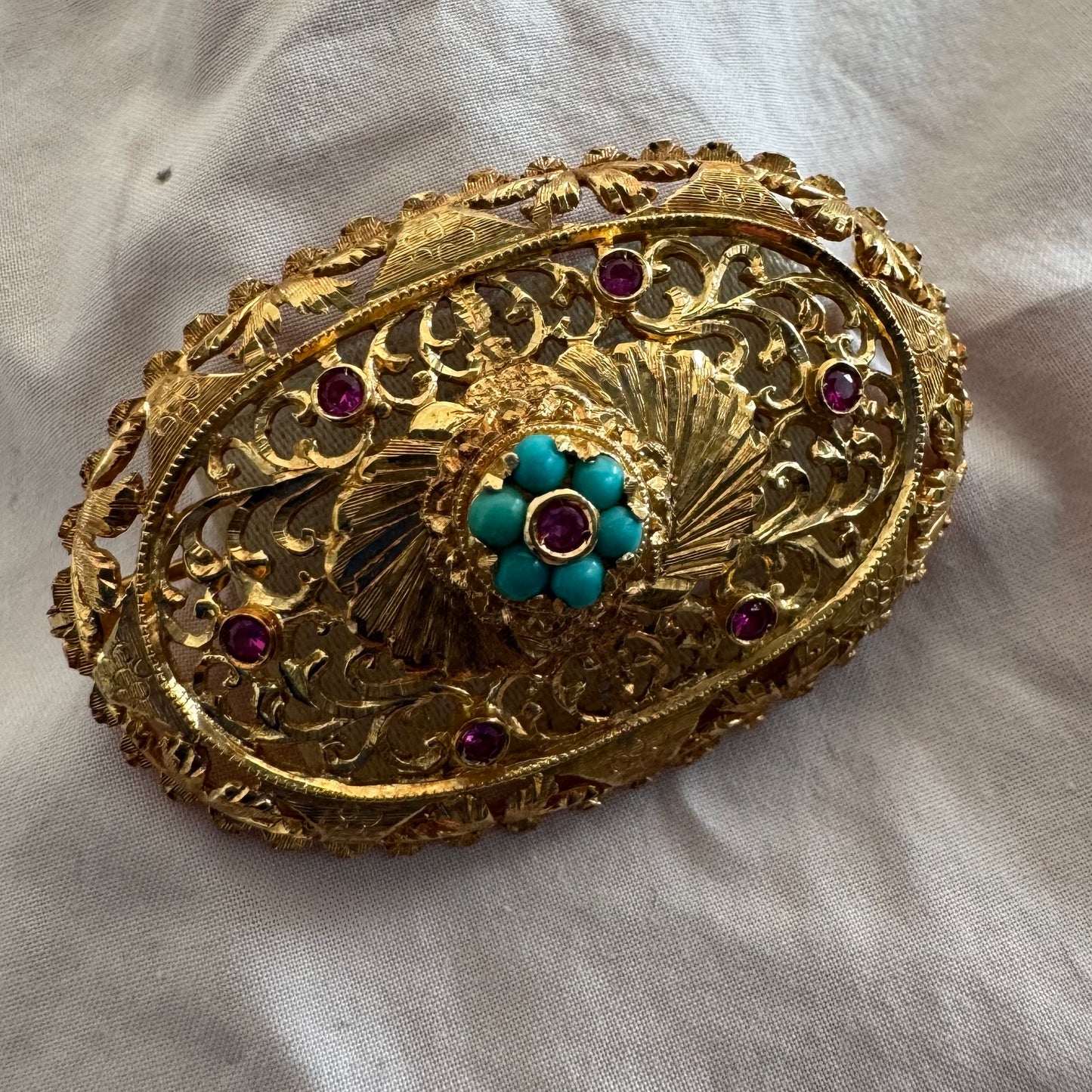18K gold filigree brooch featuring intricate openwork detailing, accented with Ruby & Turquoise arranged in a floral centerpiece