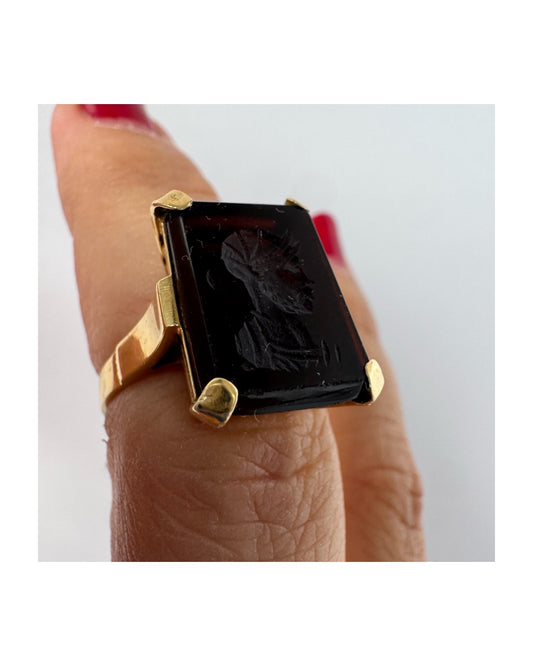 18K gold ring set with a carved dark stone featuring a classical warrior profile.