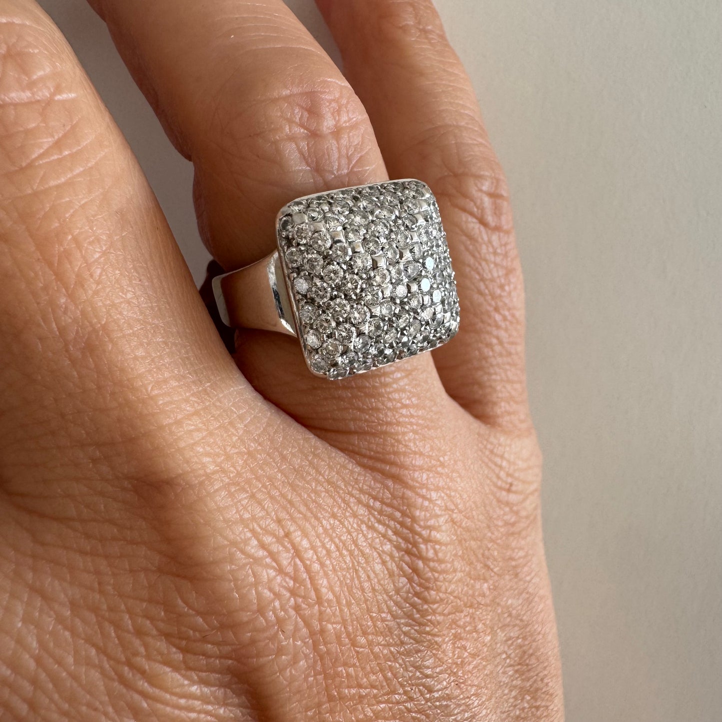 טבעת זהב לבן 18 קראט עם חלק עליון רחב בצורת ריבוע המשובץ כולו ביהלומים מנצנצים, ליצירת מראה יוקרתי ונוצץ.