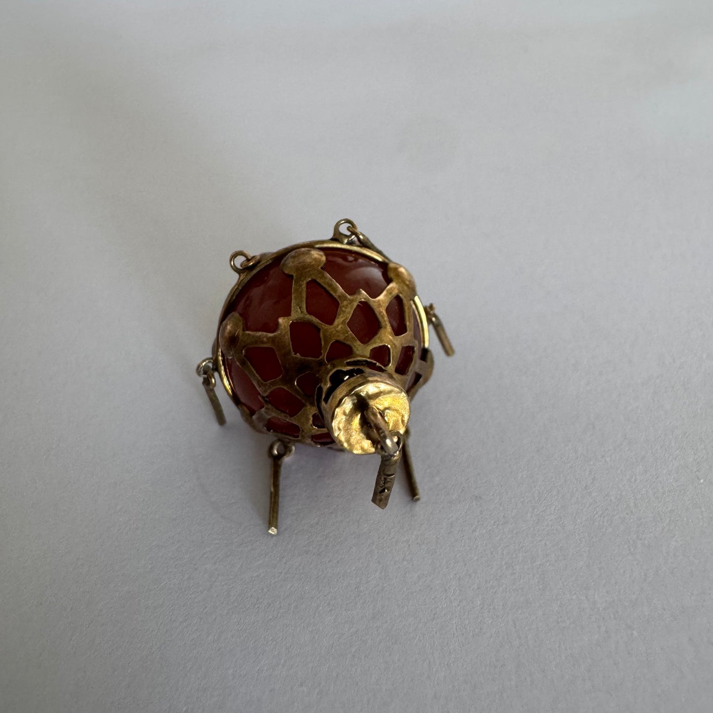 9K gold pendant set with a deep red stone in an intricate openwork design.
