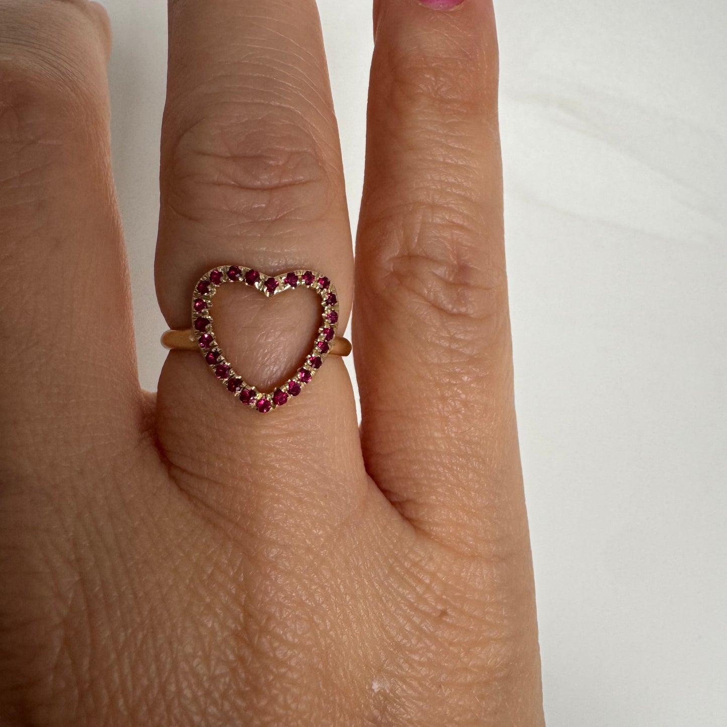 14K yellow gold open-heart ring set with deep red rubies along the frame.