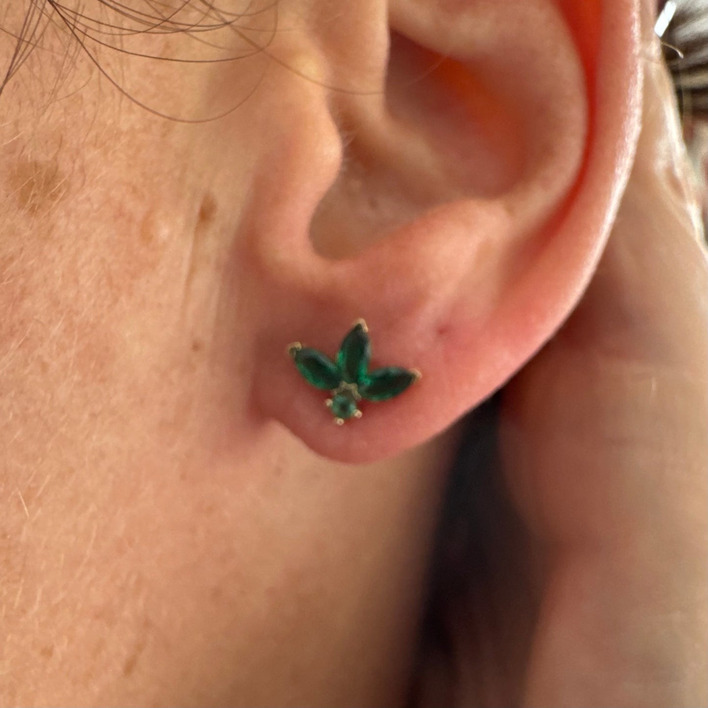 עגילים צמודיפ לאוזן מזהב 14 קראט, בעיצוב פרח עדין משובצים אבני אמרלד בחיתוך מרקיזה היוצר מראה אלגנטי, נקי ועל-זמני.