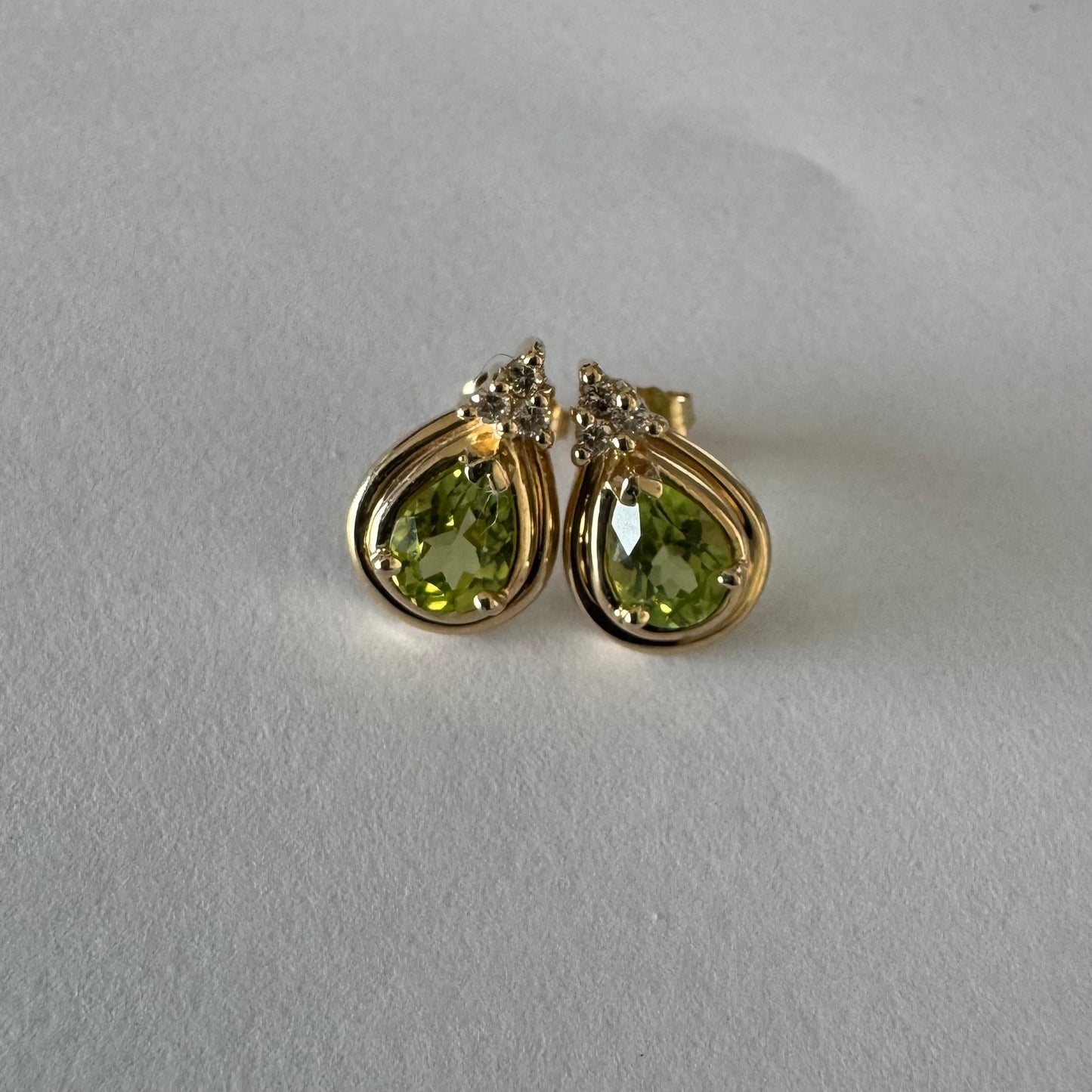 עגילי זהב צהוב 14 קראט משובצים אבני פרידוט בחיתוך טיפה, בגוון ירוק רענן ובוהק. 