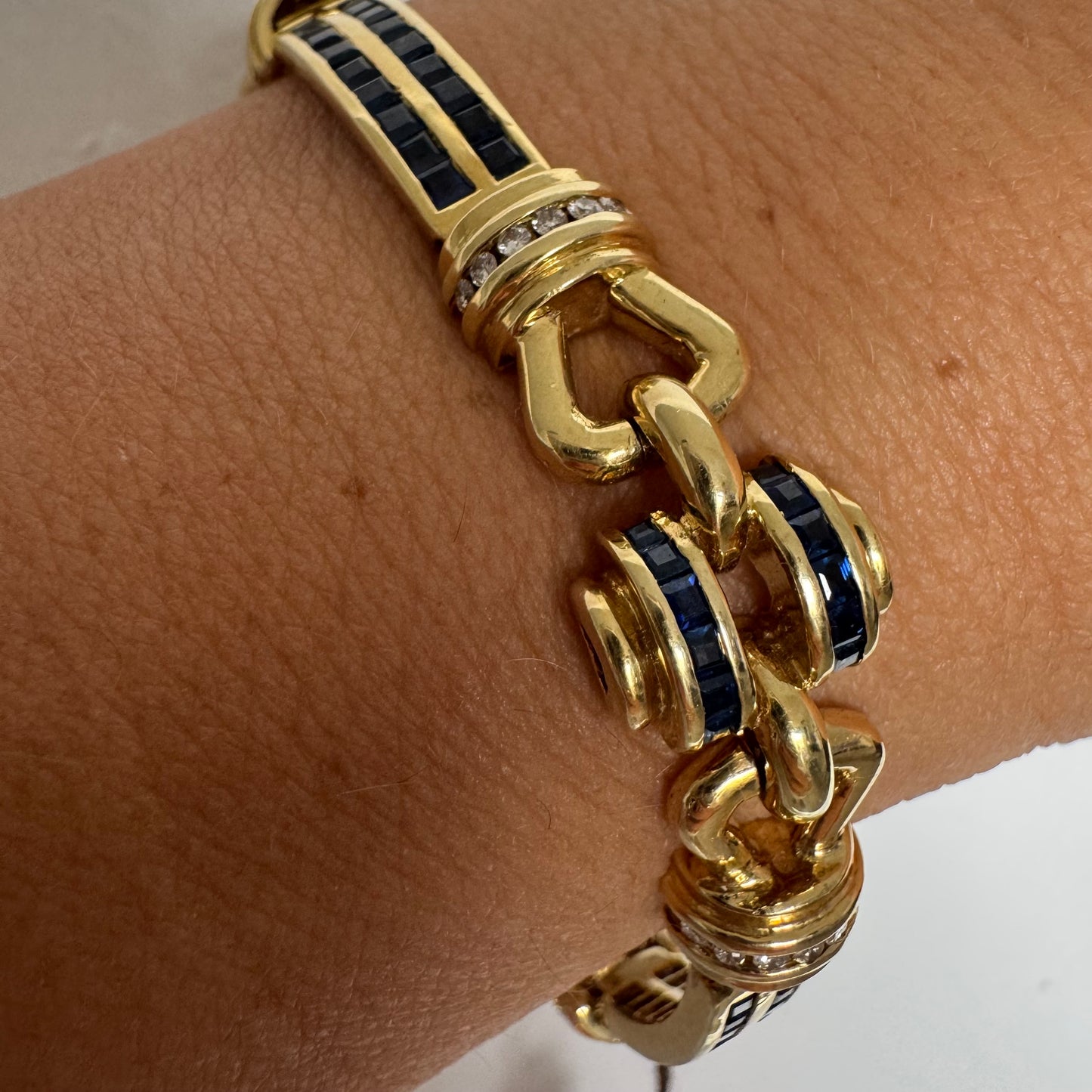 18K gold bracelet featuring a bold link design set with deep blue Sapphires and a subtle Diamond accent at the center.