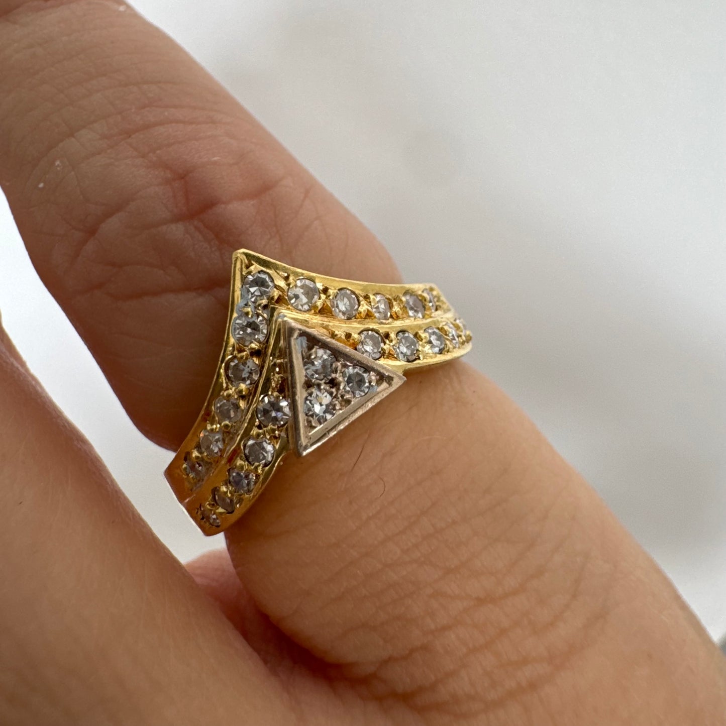טבעת זהב צהוב 18 קראט בעיצוב גאומטרי ייחודי, משובצת יהלומים נוצצים בחיתוך עגול.
