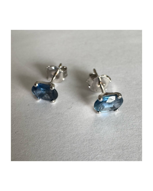 עגילי זהב לבן 14 קראט משובצים אבני טופז כחולות בחיתוך אובלי.