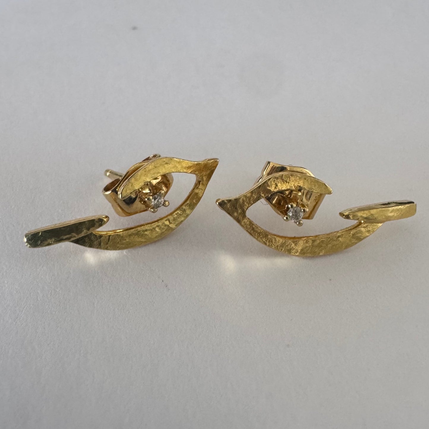 18K gold earrings in an abstract and elegant design featuring a unique handcrafted texture and a delicate Diamond set at the center