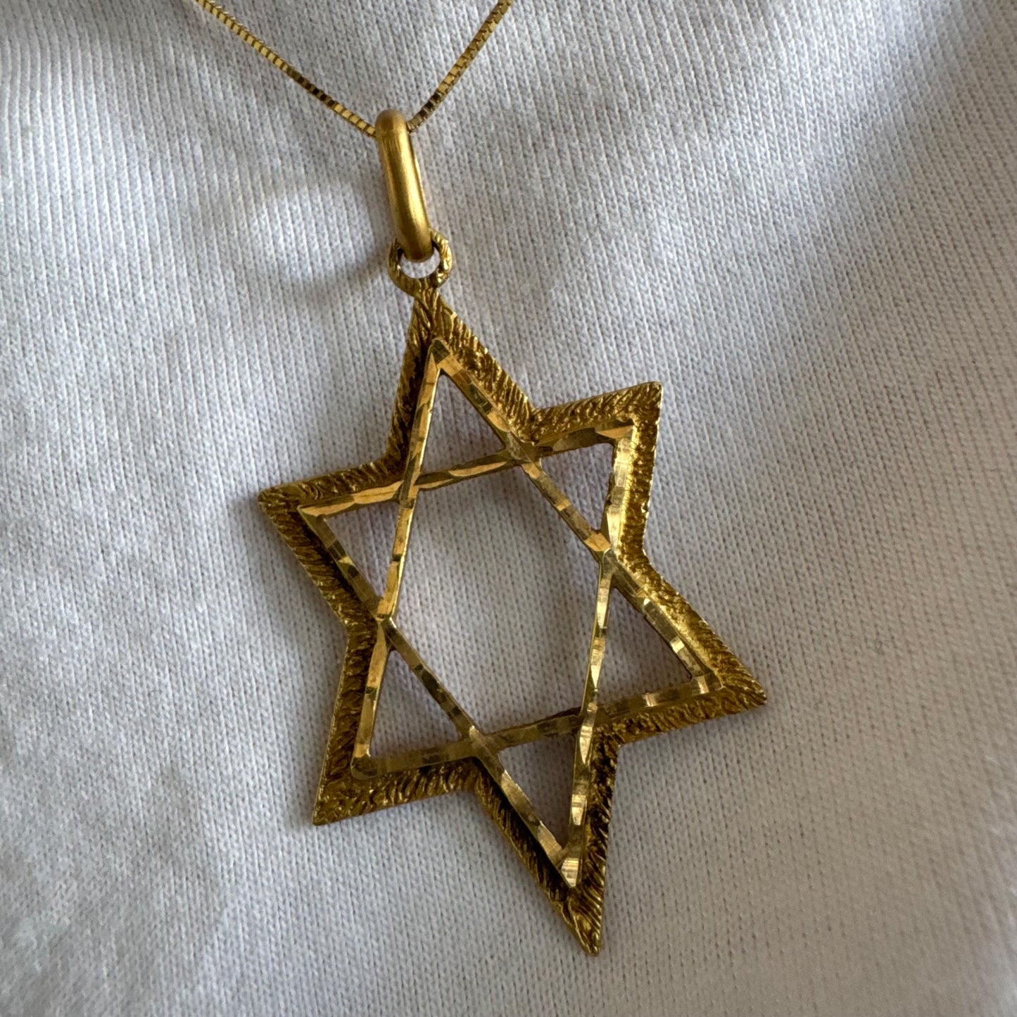 14K gold Star of David pendant with textured detailing and an open design.
