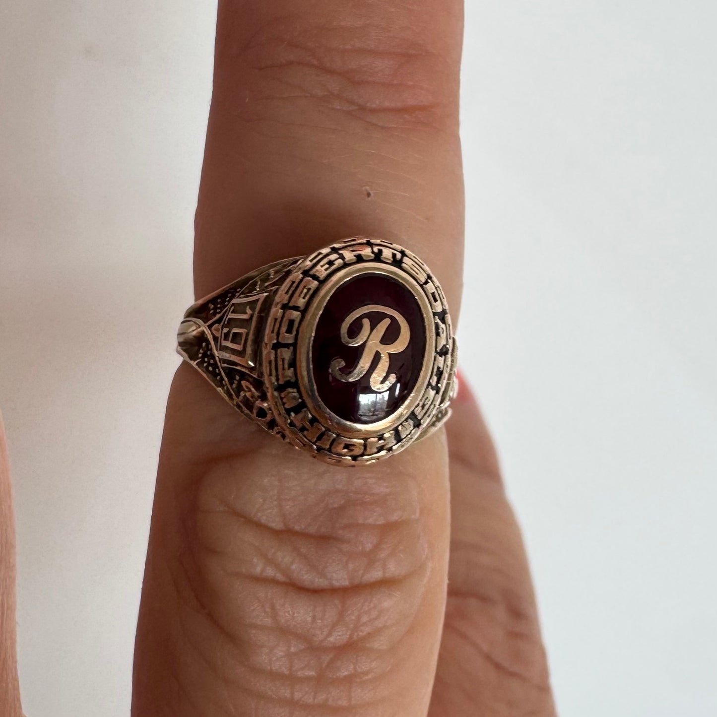 10K gold class ring featuring a rich red center stone engraved with the letter “R”.