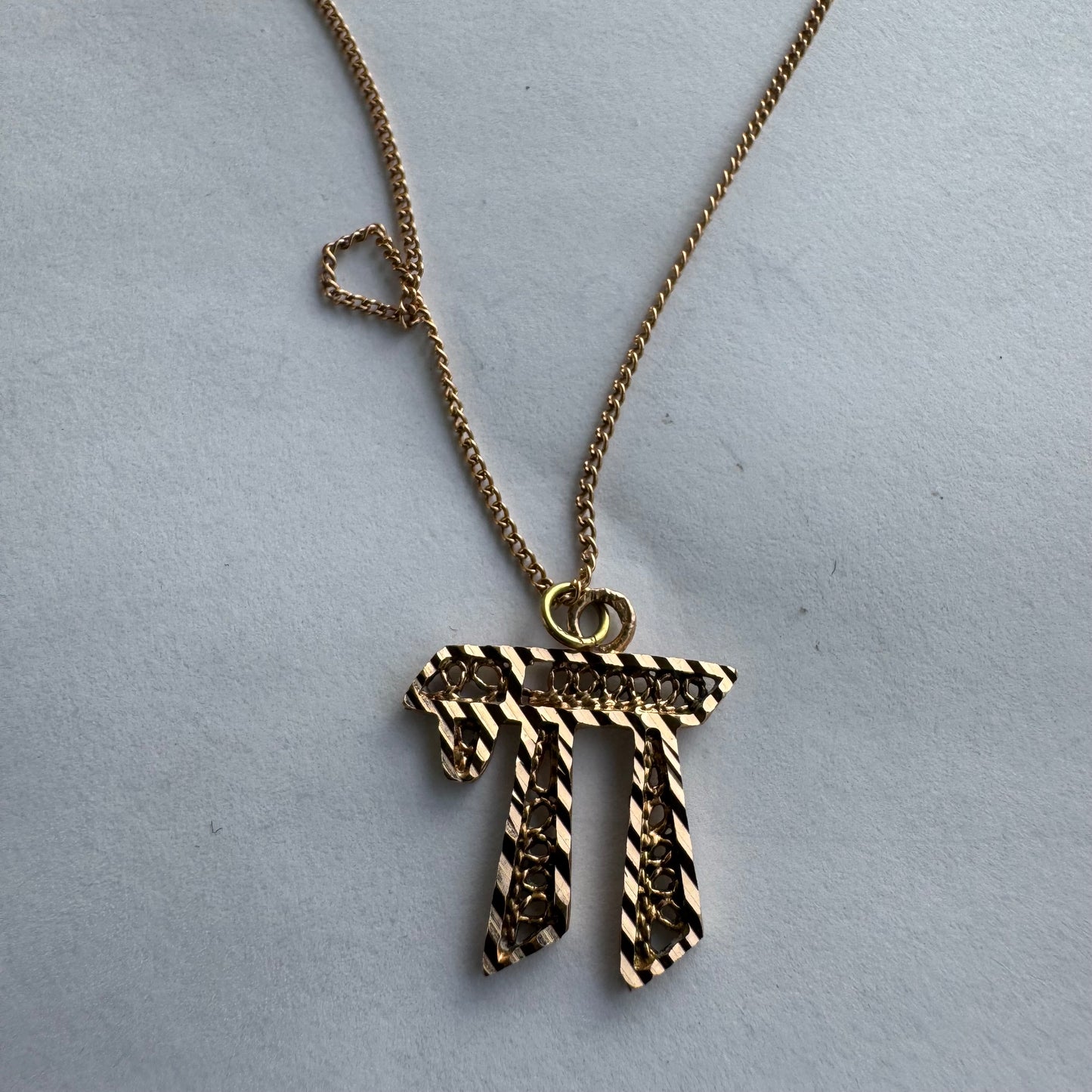 שרשרת זהב אדום 14 קראט עם תליון “חי״, בעיצוב גרפי ובעל נוכחות.