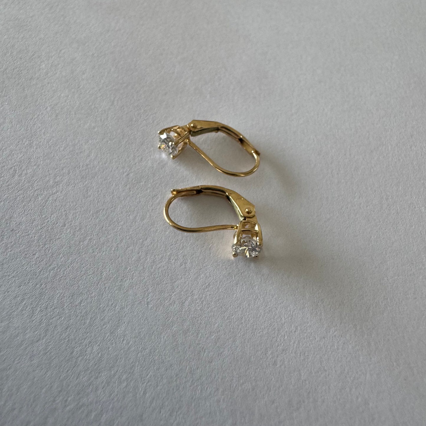 עגילי זהב 14 קראט משובצים יהלום עגול בשיבוץ קלאסי שמדגיש את האור והניקיון של האבן. 