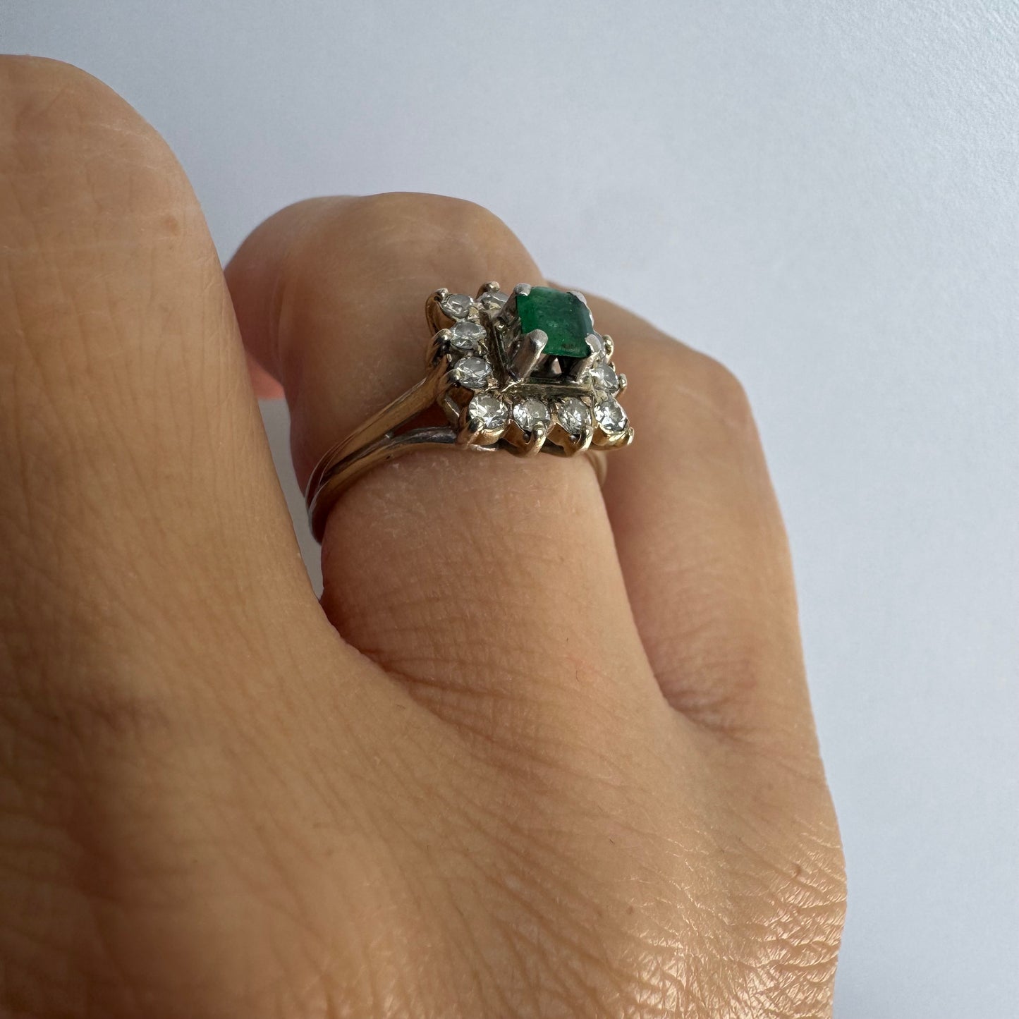 18K gold ring set with a vibrant square-cut Emerald surrounded by a sparkling halo of Diamonds.