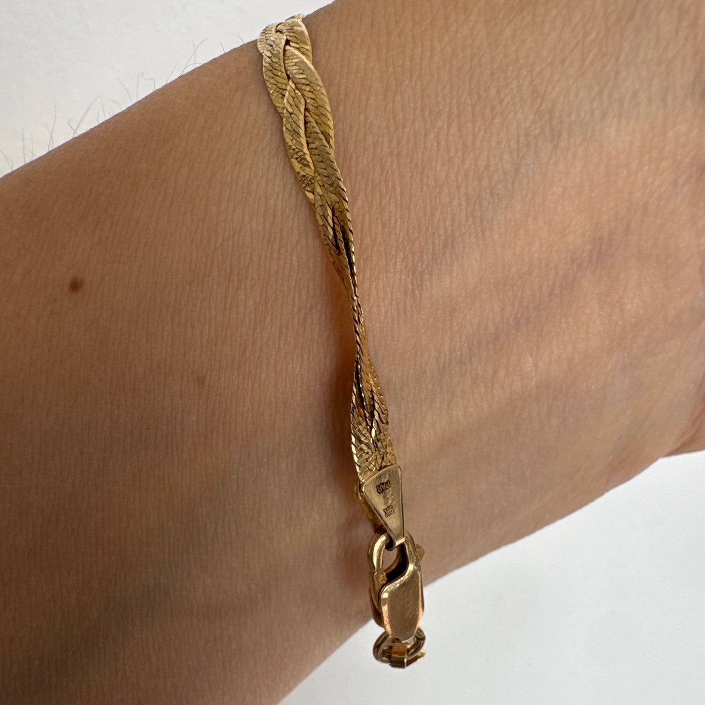 צמיד זהב צהוב 10 קראט בעיצוב קלוע עם טקסטורה עדינה שמחזירה אור וברק רך.