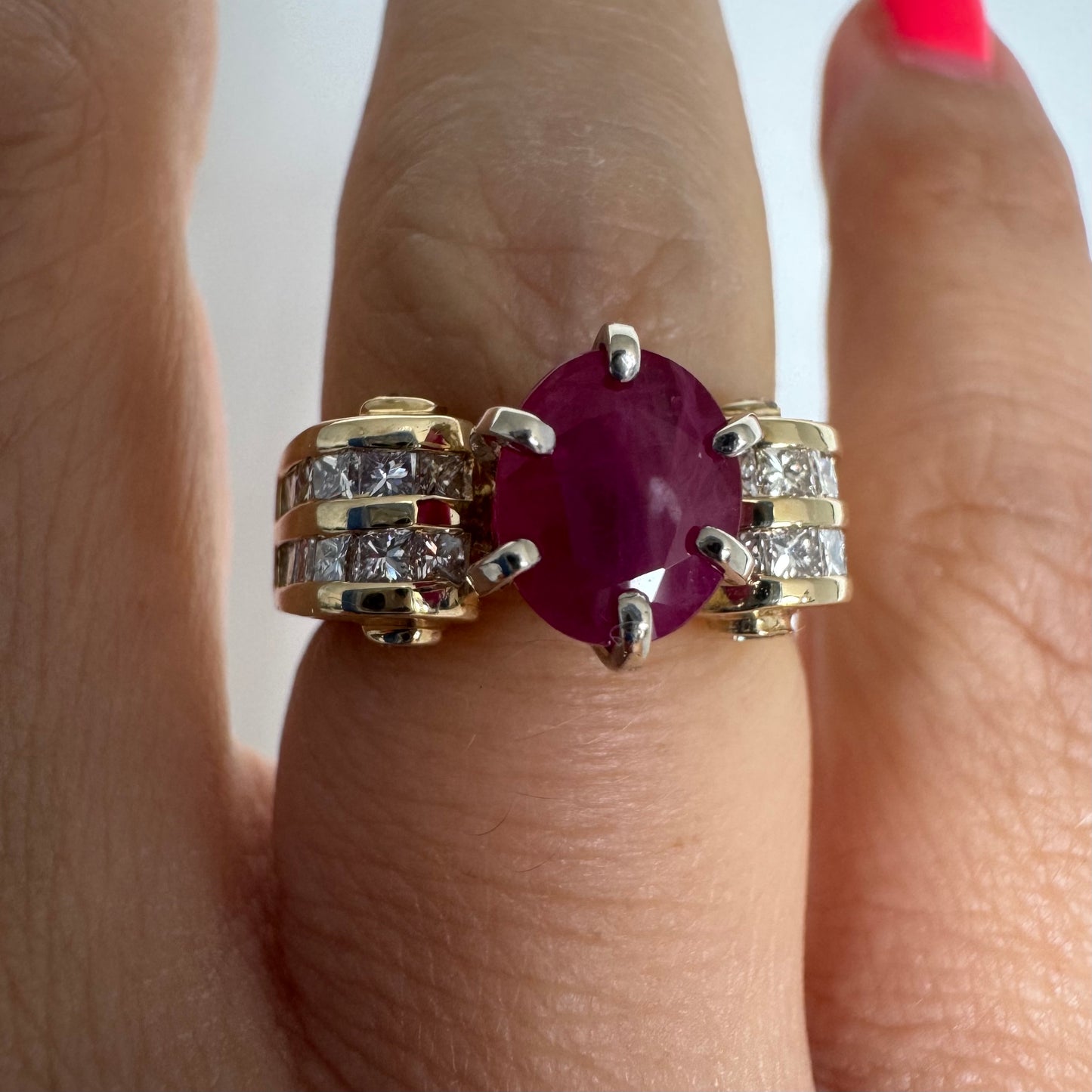 14K gold ring set with a vivid natural Ruby at the center and accented by rows of Diamonds on both sides.