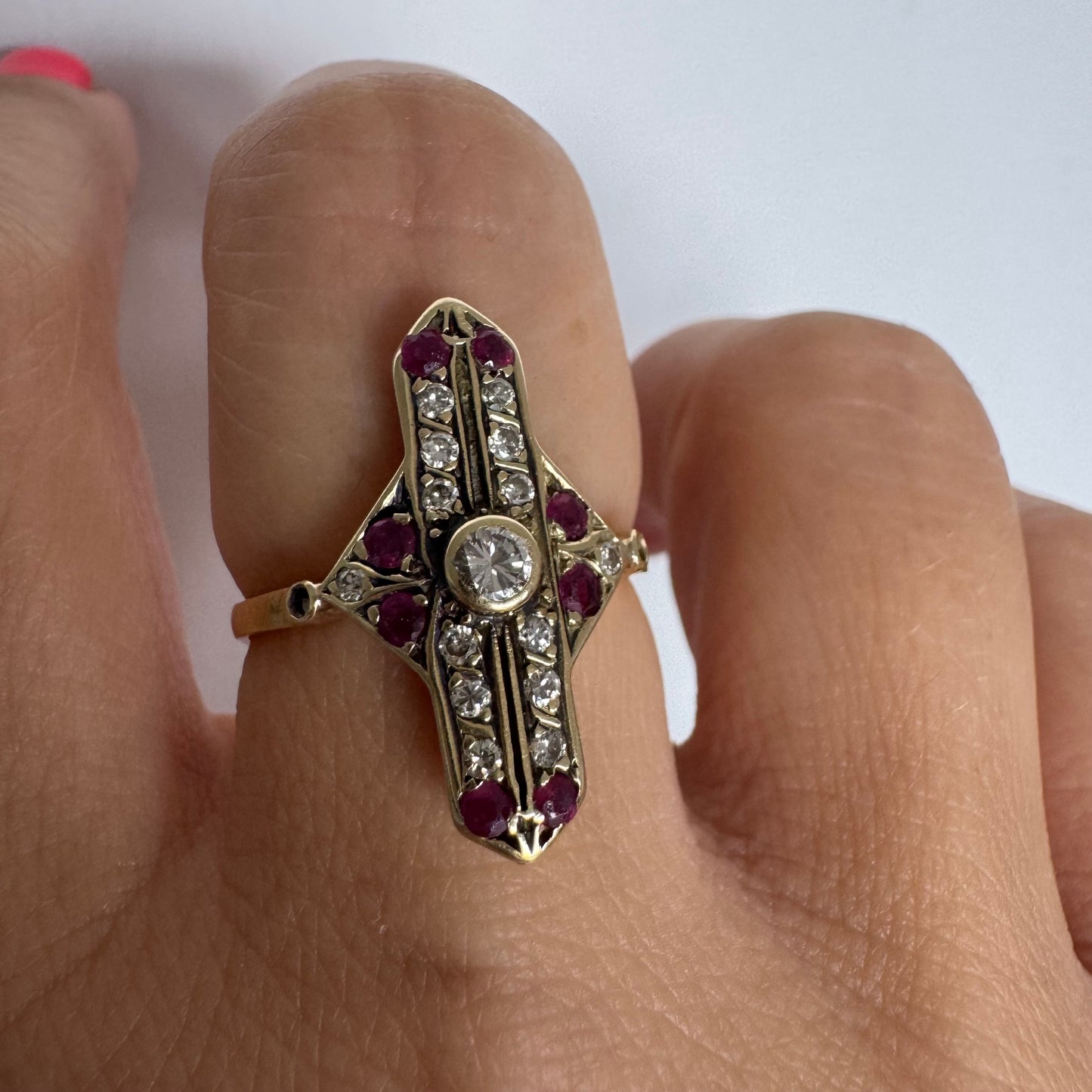 18K gold ring featuring a striking geometric design, set with a central Diamond surrounded by sparkling Diamonds and rich red Rubies.