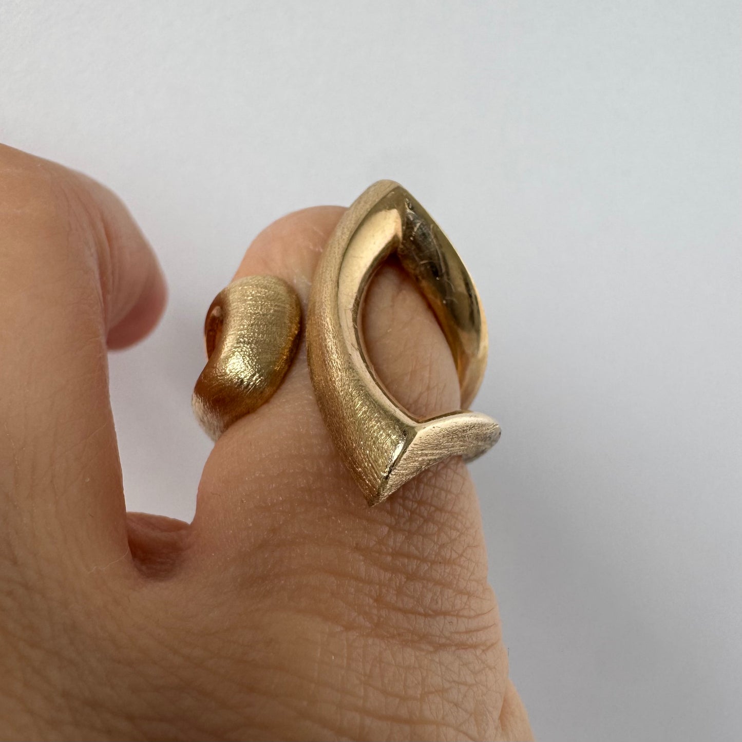 14K gold sculptural ring with a bold, modern design featuring flowing, asymmetrical lines.