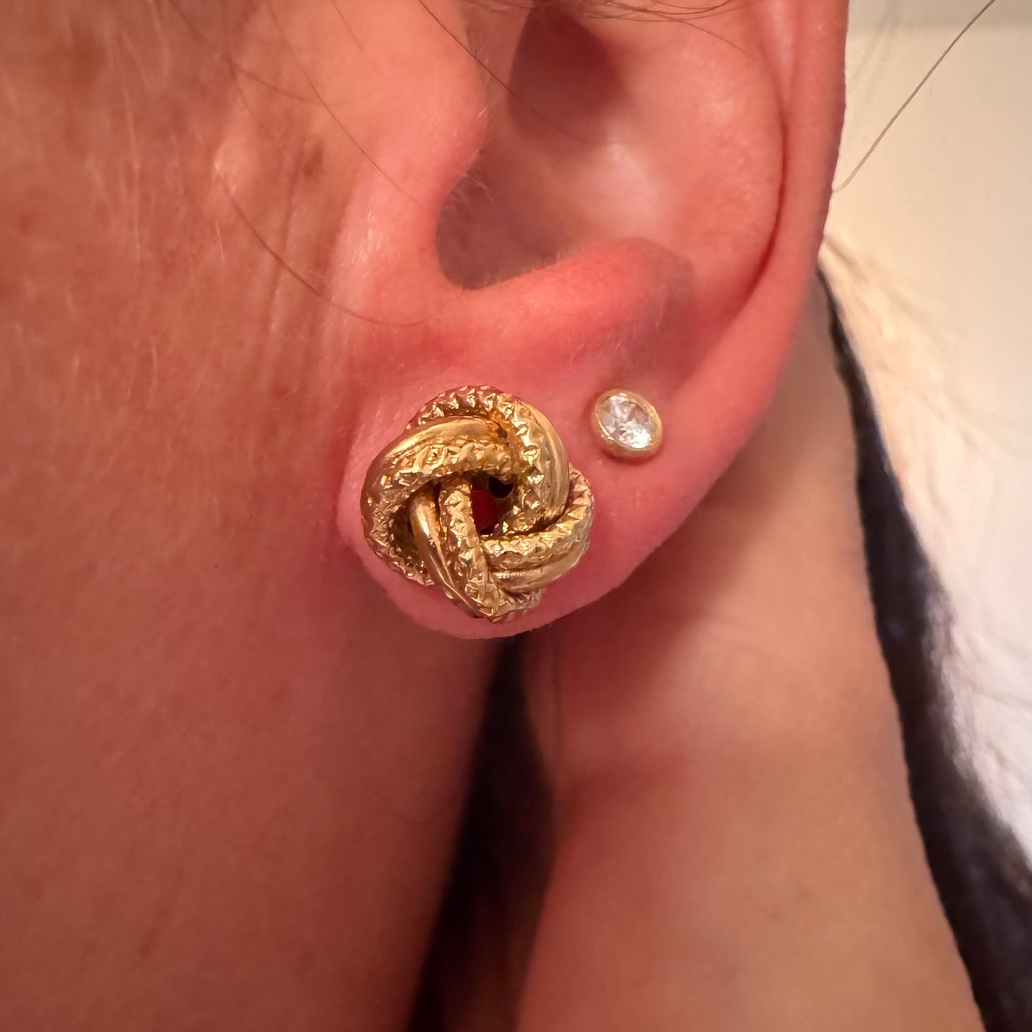 עגילי זהב צהוב 18 קראט בעיצוב קשר פיסולי, עם טקסטורה עשירה המדגישה את עומק וצורת הזהב.