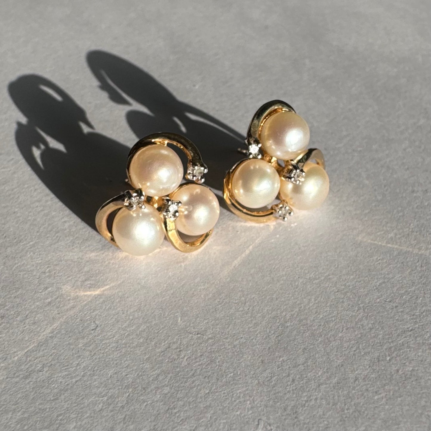 10K gold stud earrings in a delicate floral design, set with three creamy natural Pearls & Diamonds.