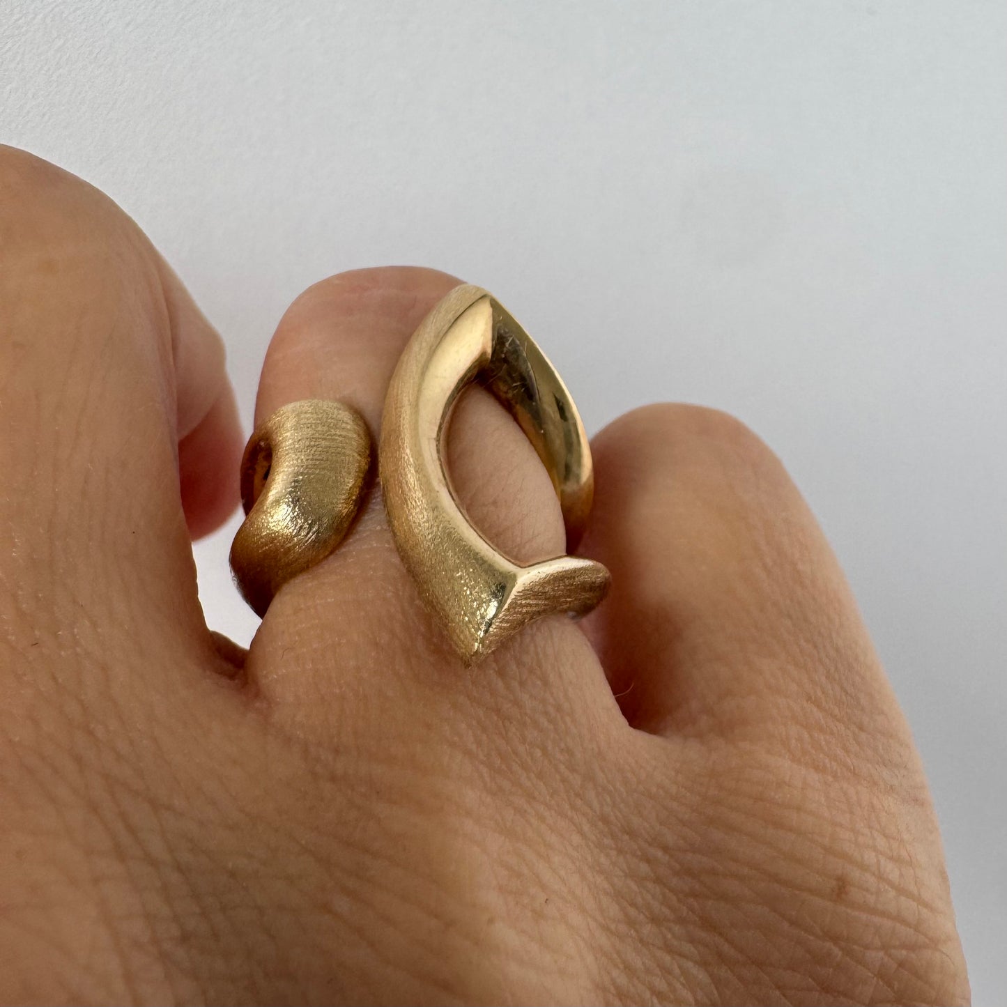 14K gold sculptural ring with a bold, modern design featuring flowing, asymmetrical lines.