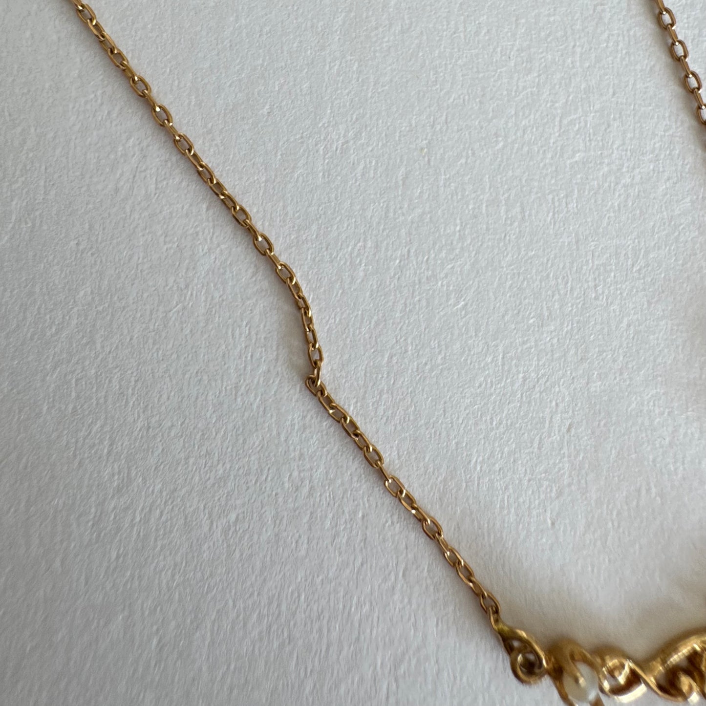 18K gold Necklace featuring an elegant scrollwork design and a striking deep-red pear-shaped Garnet drop.