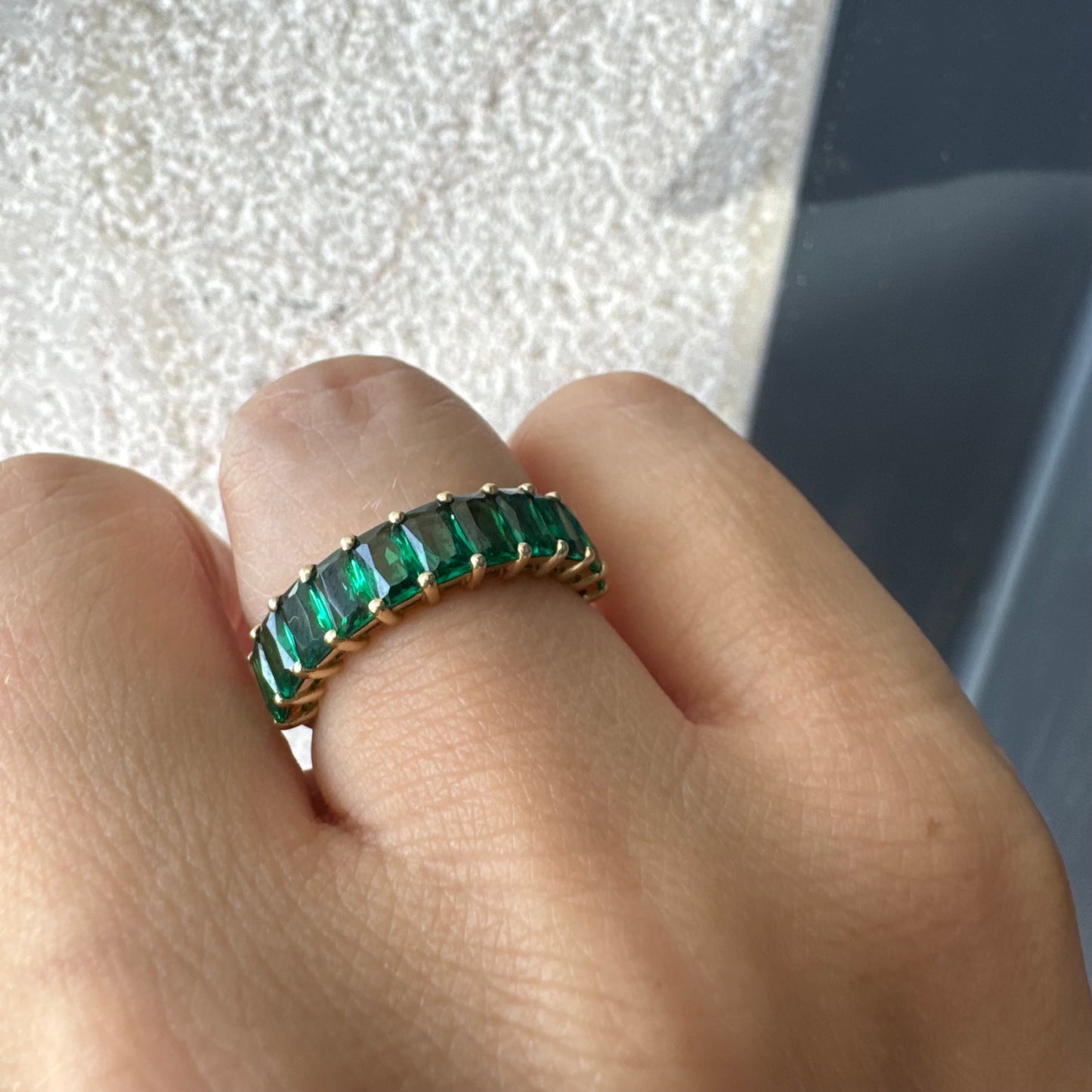 טבעת זהב צהוב 14 קראט משובצת אבנים ירוקות בחיתוך אמרלד, בעיצוב חצי איטרניטי.