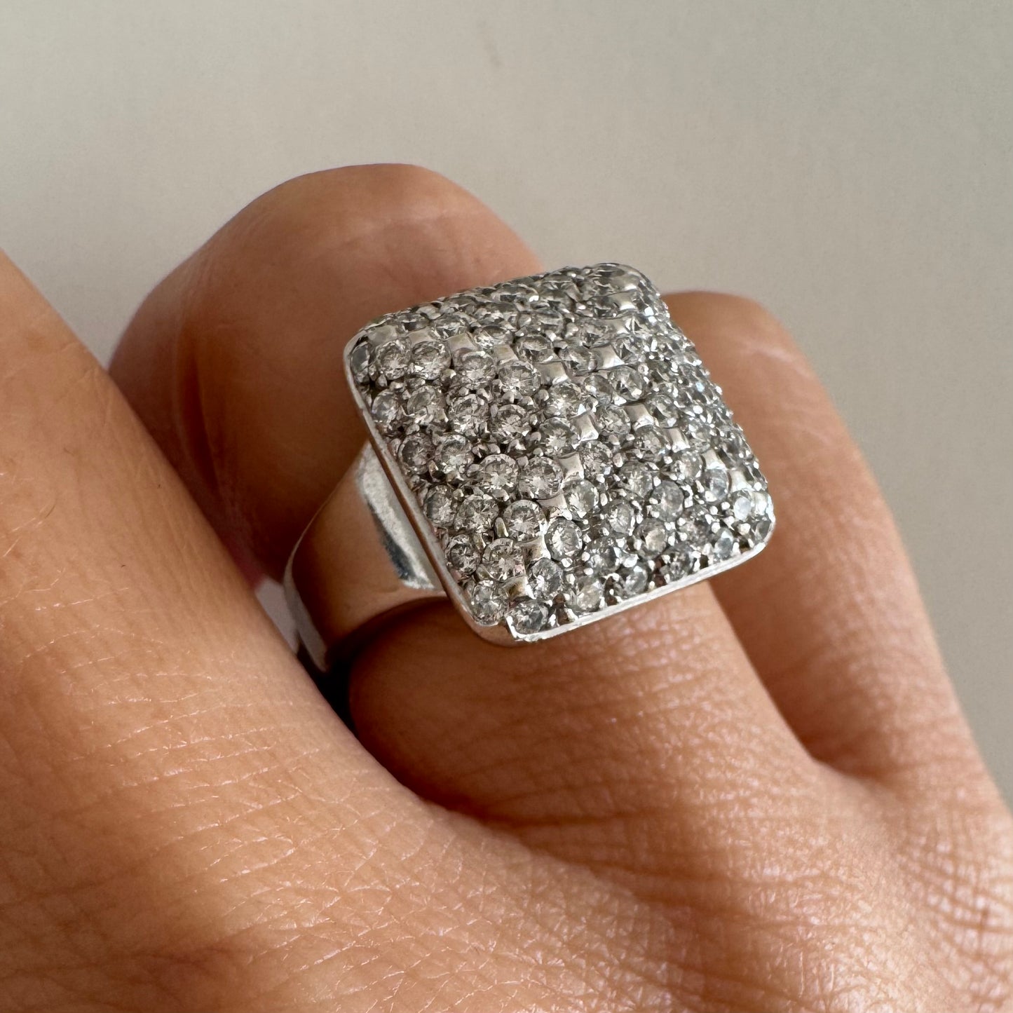 טבעת זהב לבן 18 קראט עם חלק עליון רחב בצורת ריבוע המשובץ כולו ביהלומים מנצנצים, ליצירת מראה יוקרתי ונוצץ.