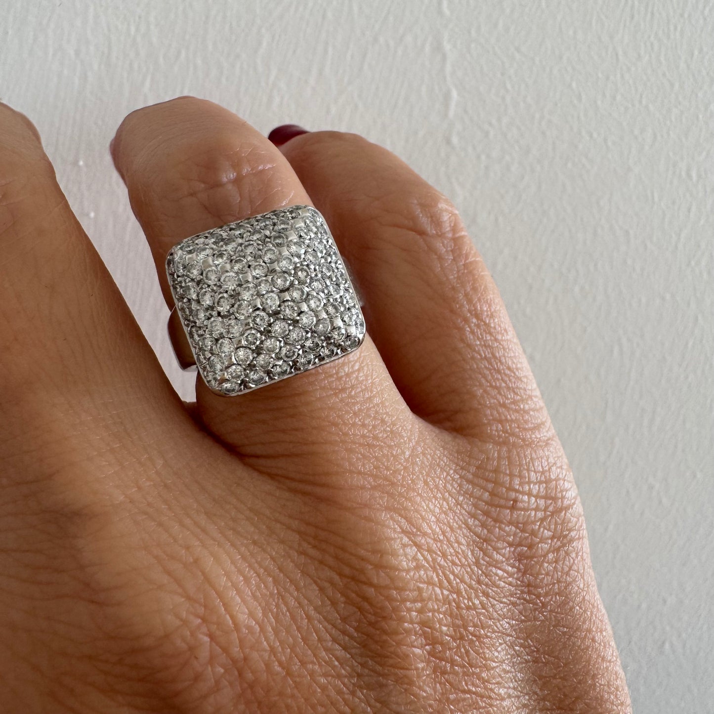 טבעת זהב לבן 18 קראט עם חלק עליון רחב בצורת ריבוע המשובץ כולו ביהלומים מנצנצים, ליצירת מראה יוקרתי ונוצץ.