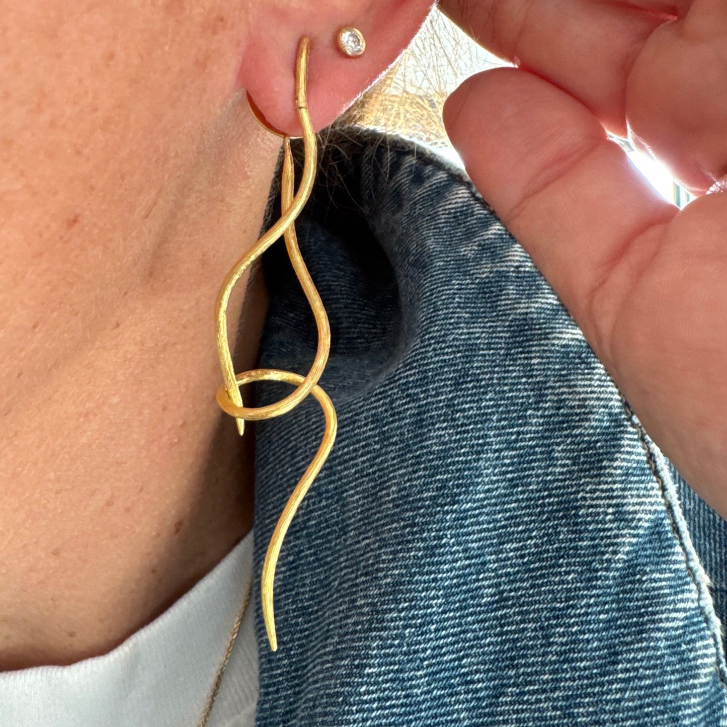 עגילי זהב צהוב 18 קראט מבית ה.שטרן, בעיצוב פיסולי וייחודי עם קווים זורמים ודינמיים.