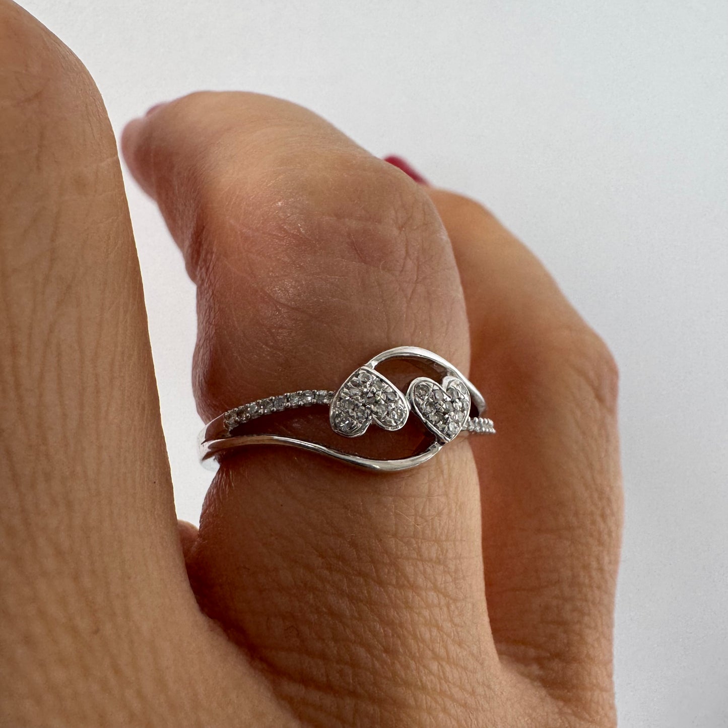14K gold ring featuring a delicate and romantic design with two connected diamond hearts