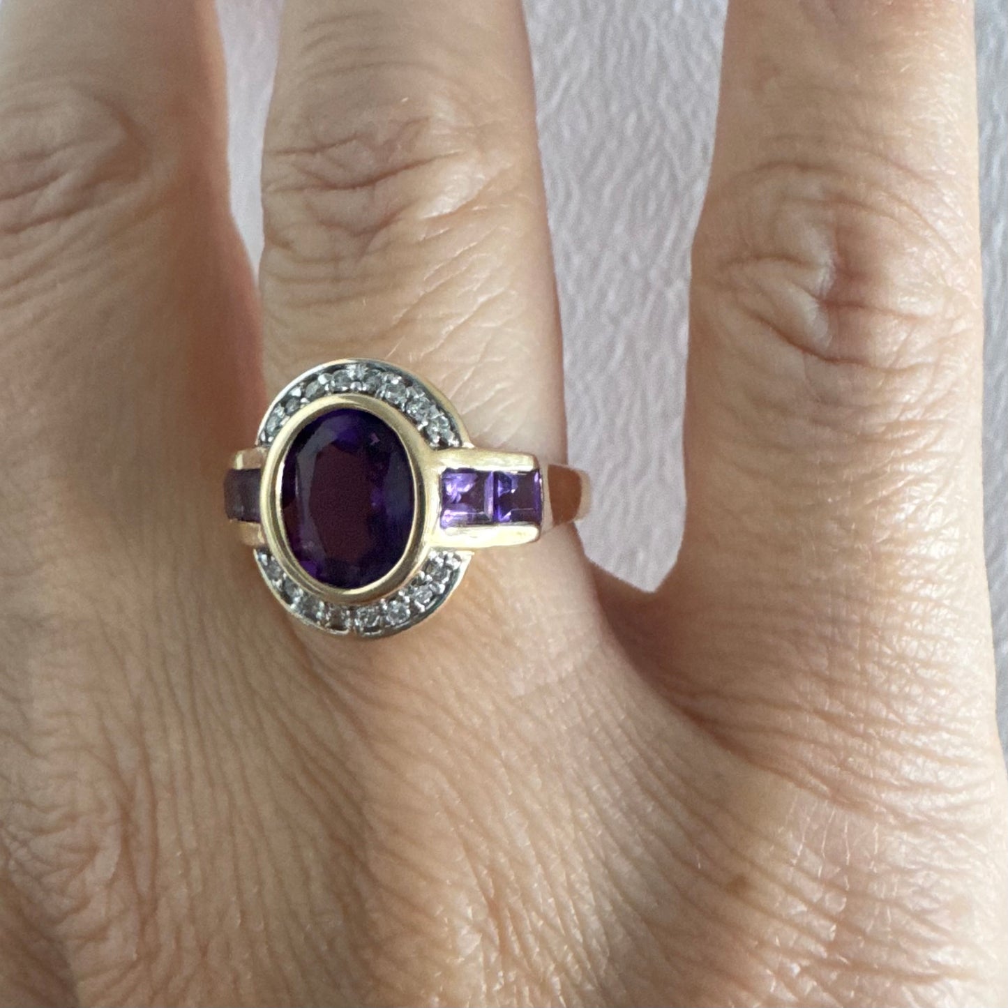 טבעת זהב 14 קראט בעיצוב ייחודי עם אבן אמטיסט אובלית מרכזית בגוון סגול עמוק, משובצת במסגרת חלקה ומודגשת ויהלומים.