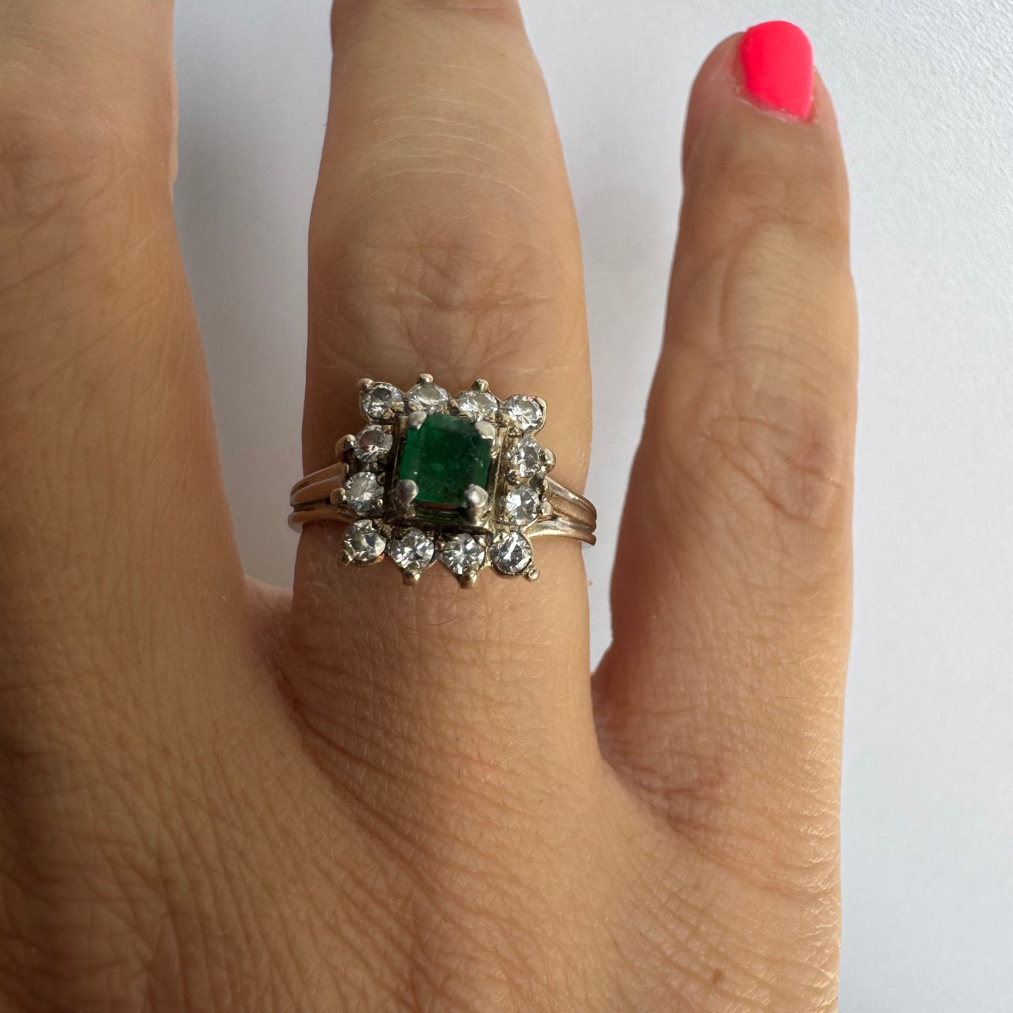 18K gold ring set with a vibrant square-cut Emerald surrounded by a sparkling halo of Diamonds.