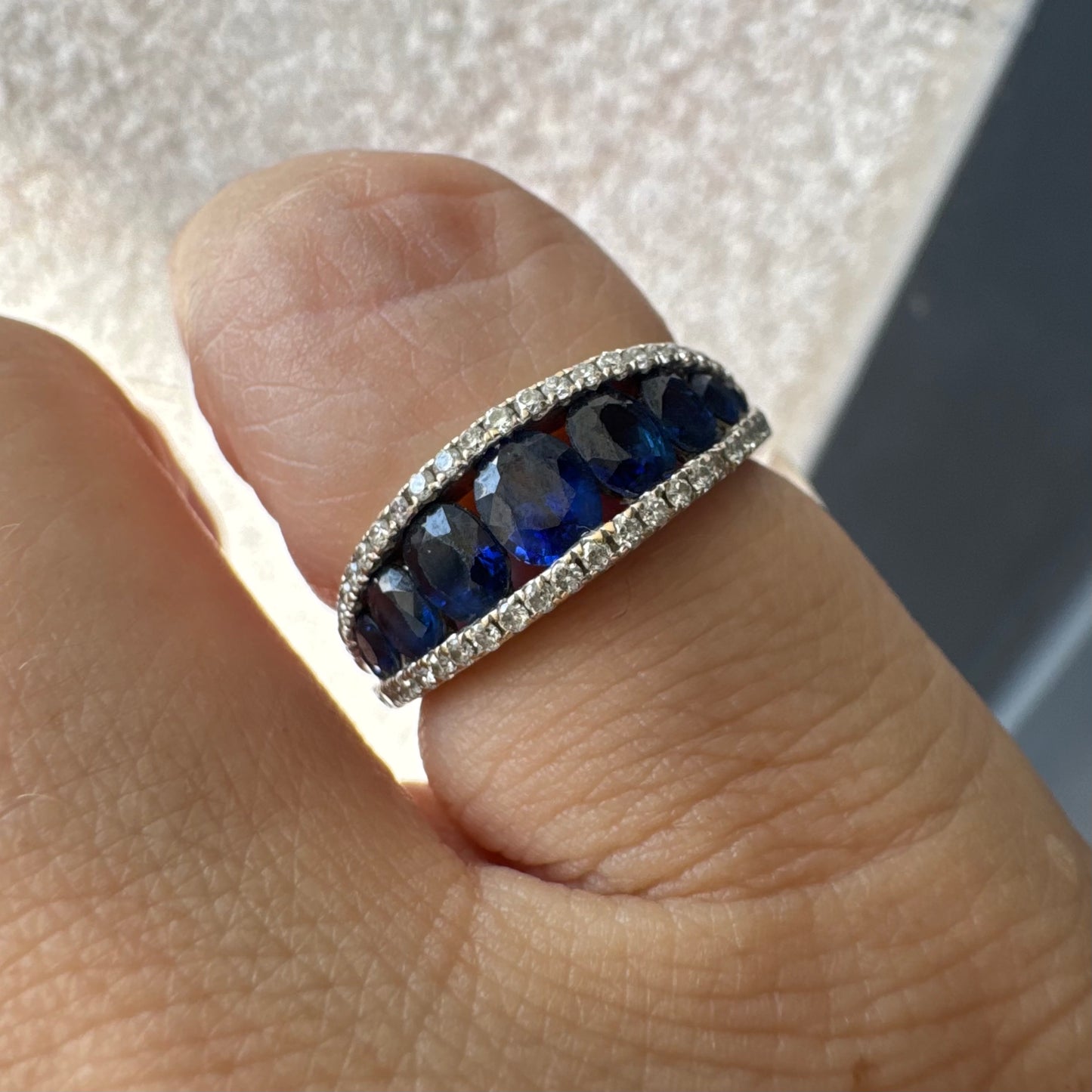 טבעת זהב צהוב 18 קראט משובצת שורת אבני ספיר כחולות בליטוש אובלי, משובצות במרכז ומוקפות בשתי שורות של יהלומים אחת מעל ואחת מתחת.