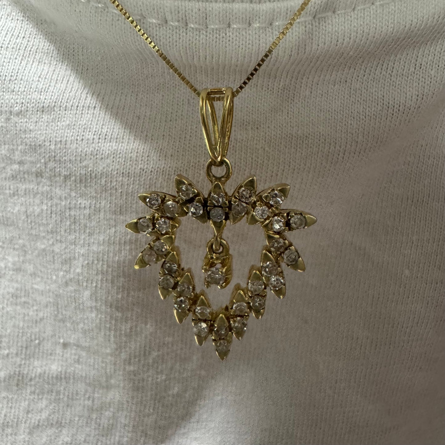 תליון זהב צהוב 14 קראט בצורת לב, משובץ יהלומים בסידור עדין היוצר מראה עשיר ומלא ברק.